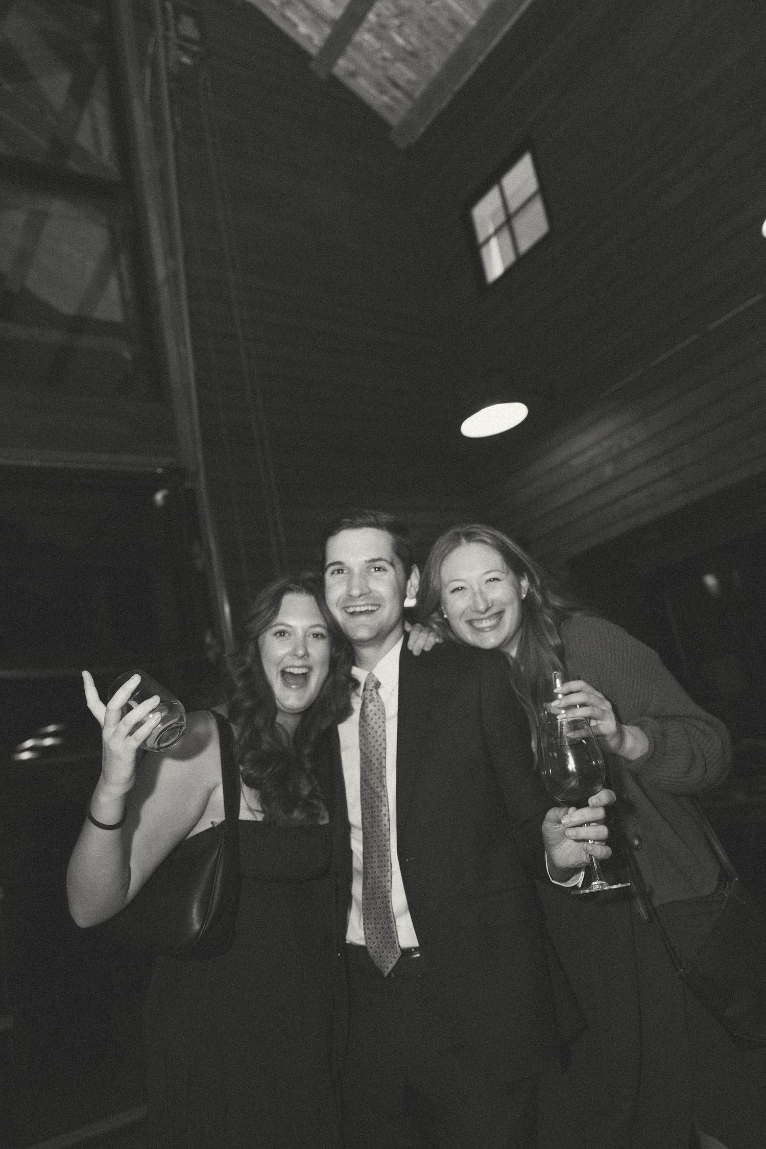 Group of wedding guests laughing and having fun in a dark reception venue.