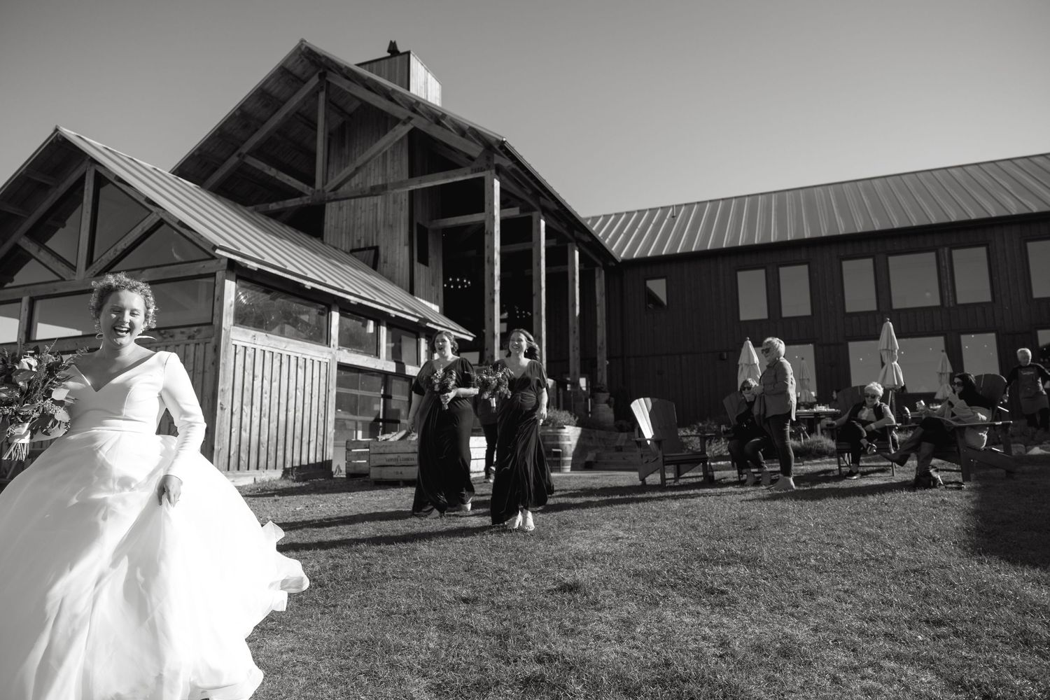 Panoramic view of a wedding celebration outside a wooden barn structure.