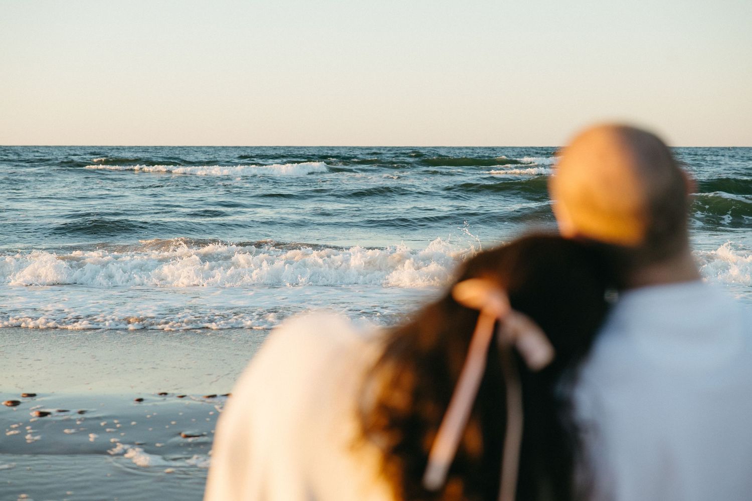 Waves crash on a sandy beach at sunset creating a peaceful coastal scene.