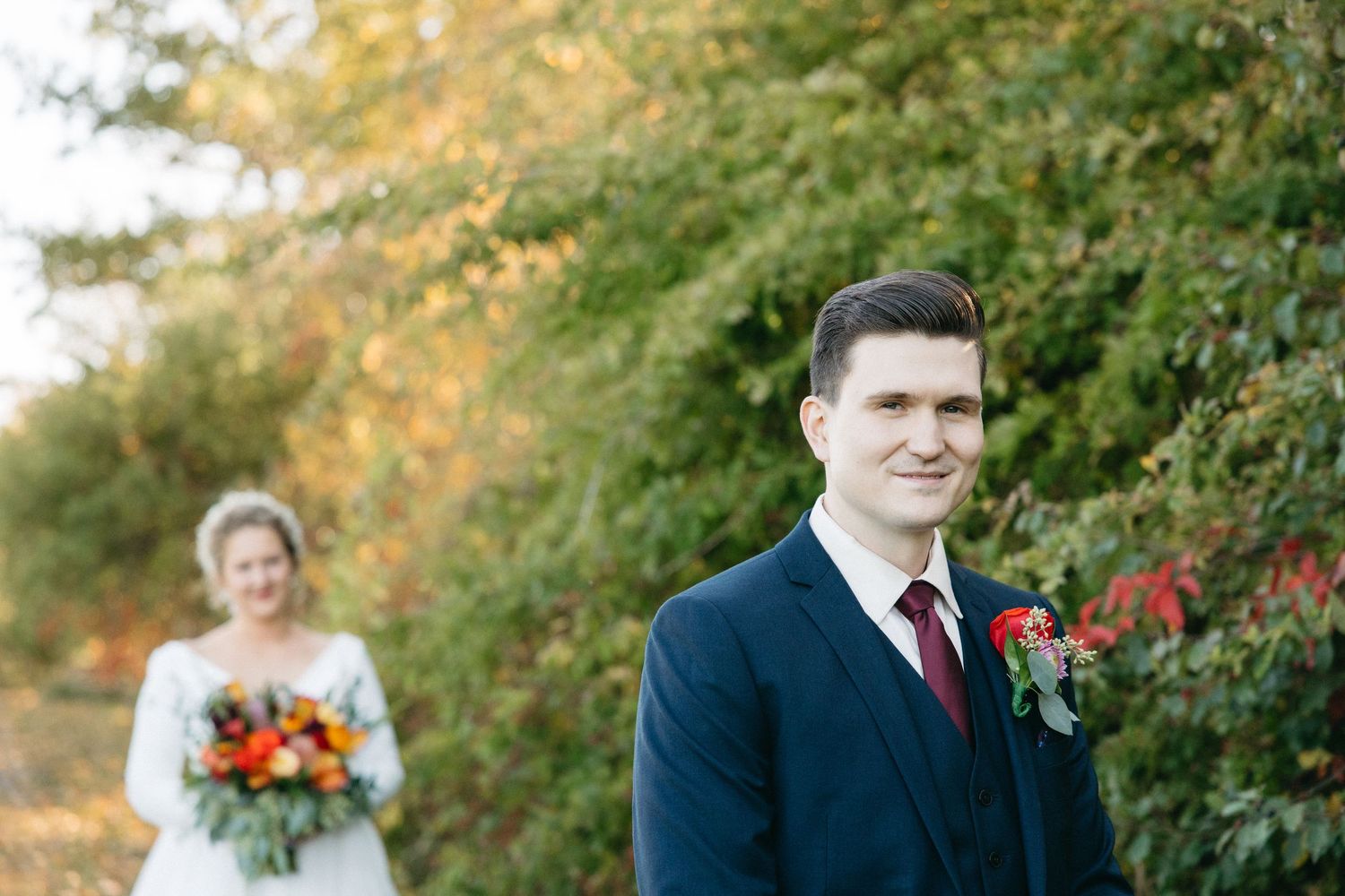 Wedding couple walking together outdoors with autumn foliage and natural lighting.