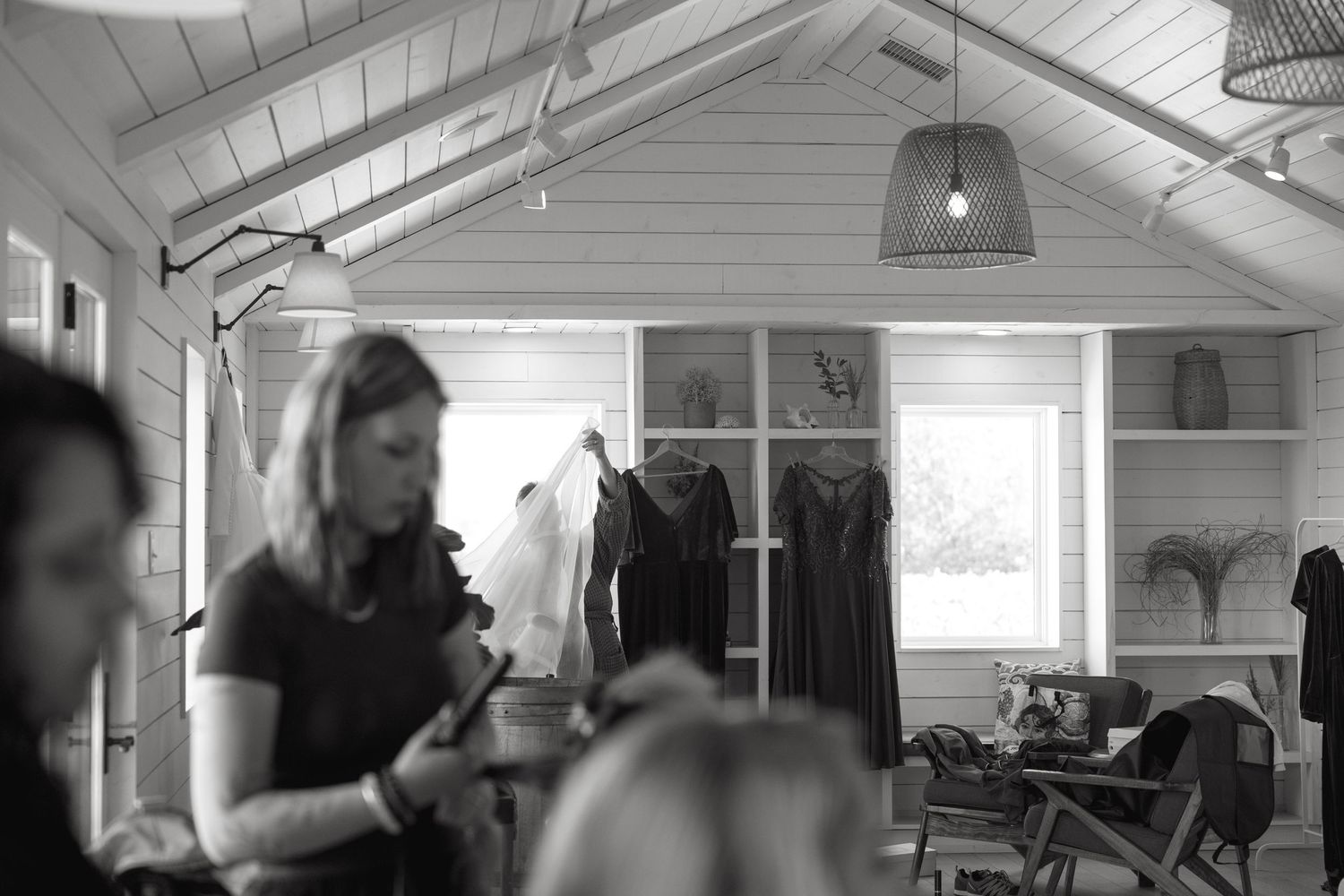 Interior of bright white room with vaulted ceiling and clothing racks.