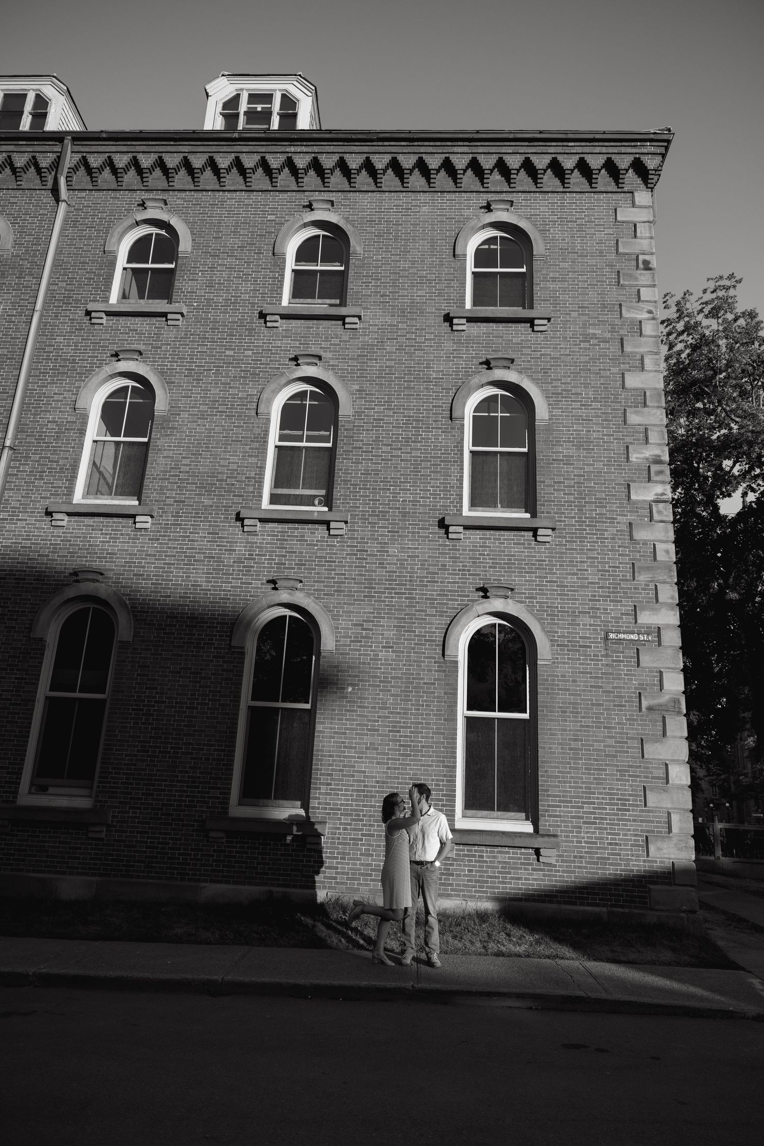 A dramatic black and white series showing a couple against a Gothic brick building facade.