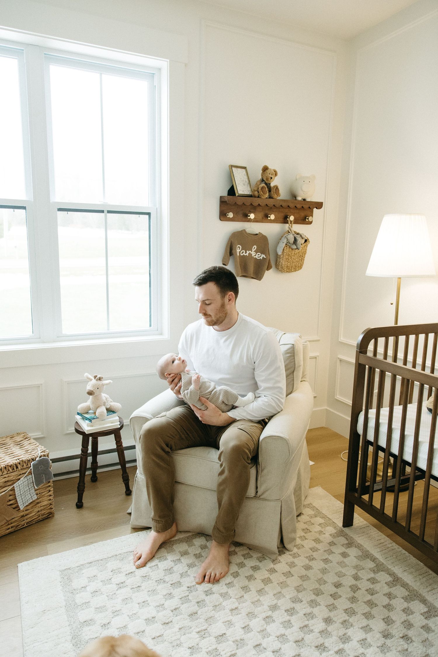 Bright nursery room with white walls, patterned rug, and wooden crib.