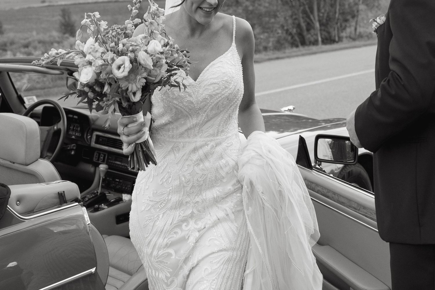 White wedding dress and bouquet details captured near vintage automobiles.