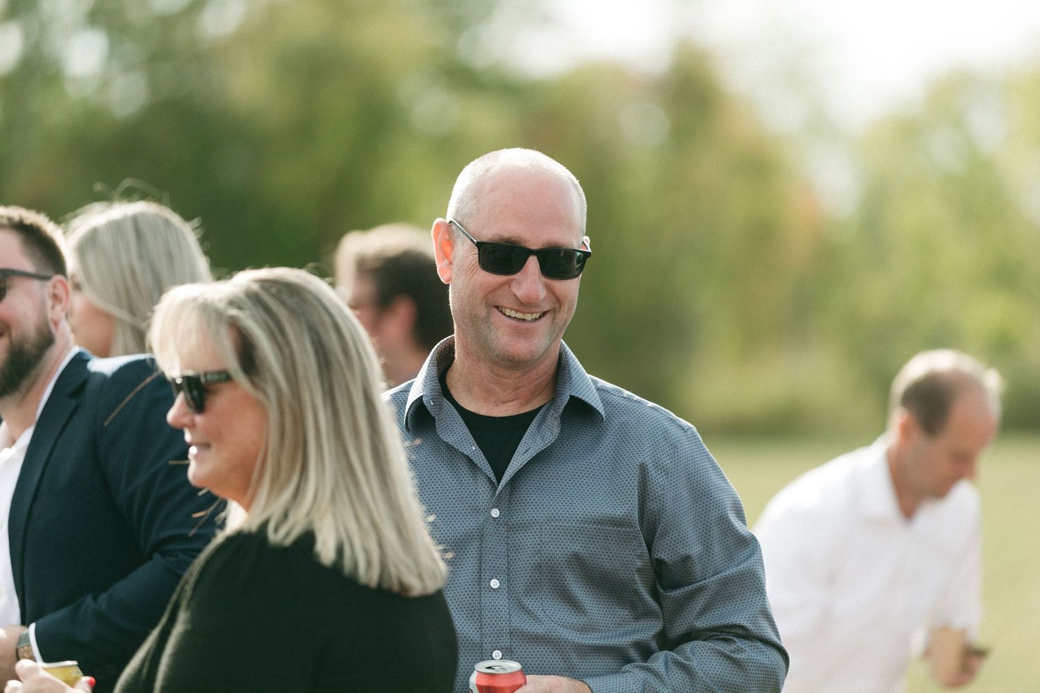 Wedding guests socialize on sunny patio during outdoor reception.