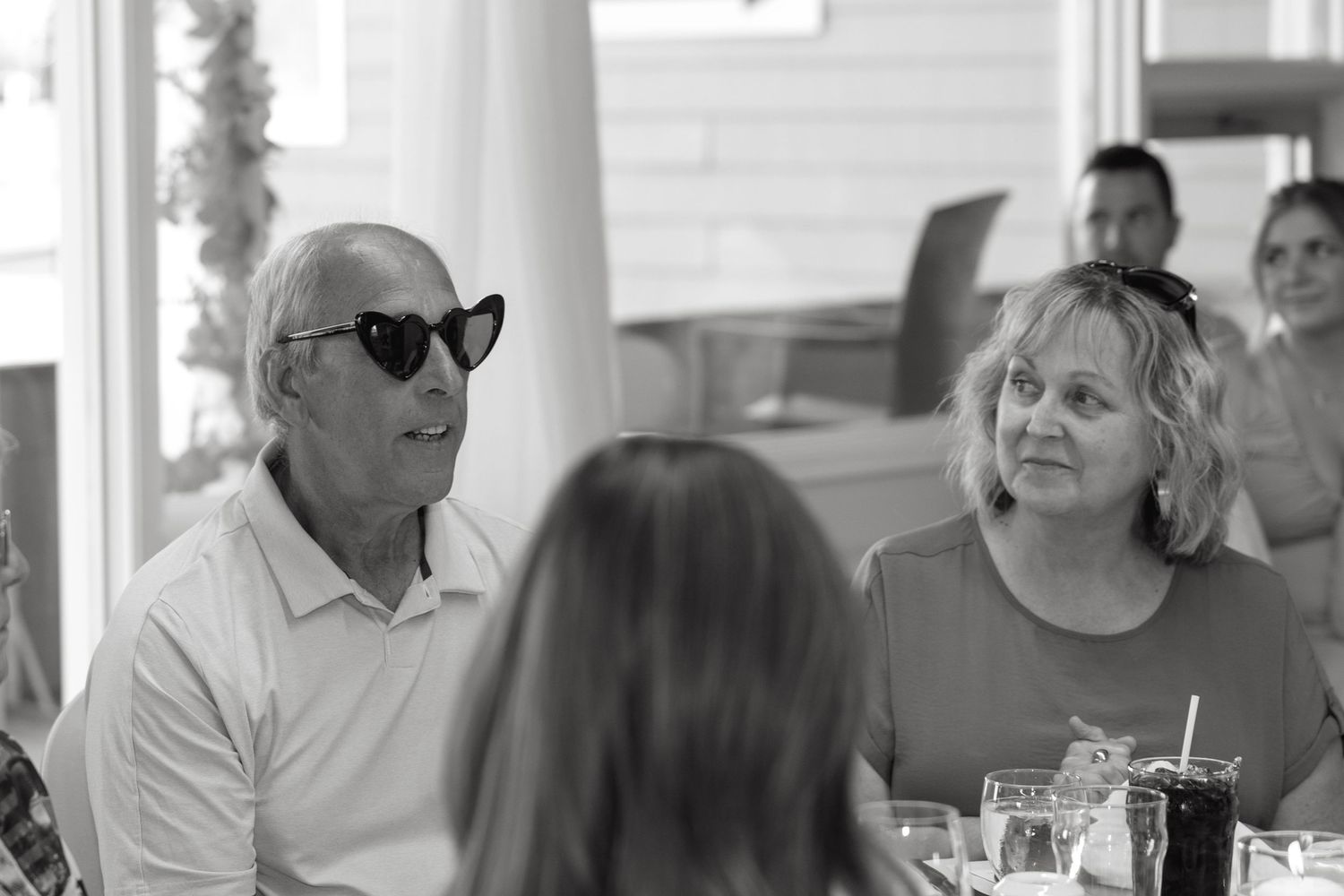 Wedding guests enjoying a meal at tables in a bright indoor reception venue.