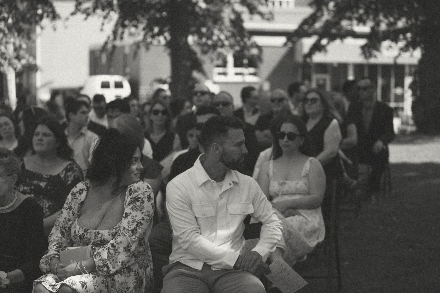 Black and white photo of wedding guests seated during outdoor ceremony.