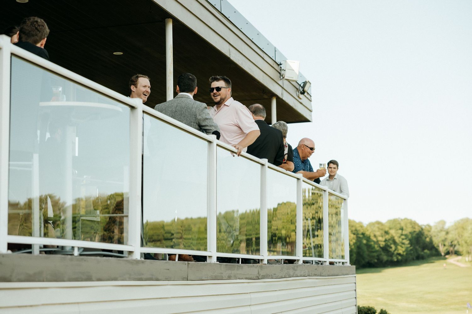 Modern wedding venue exterior with glass windows and guests viewing from above.