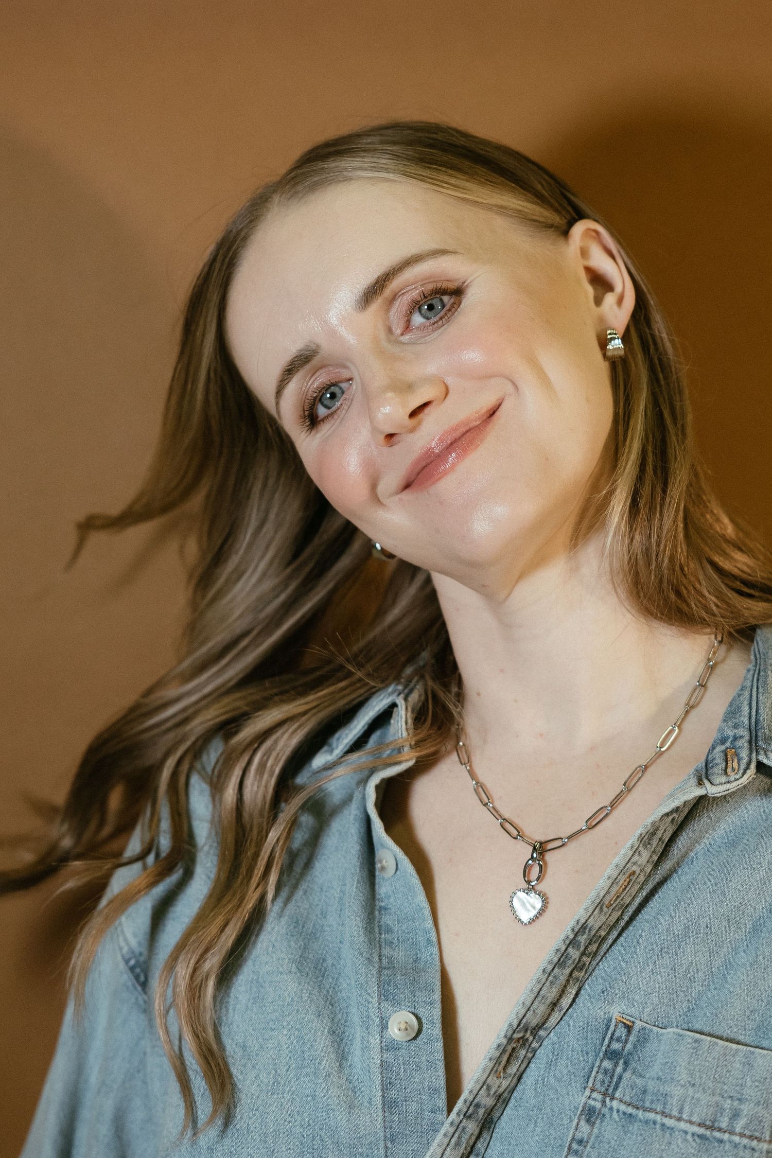 Close-up portrait series showing someone wearing a denim shirt and silver heart necklace against a brown background.