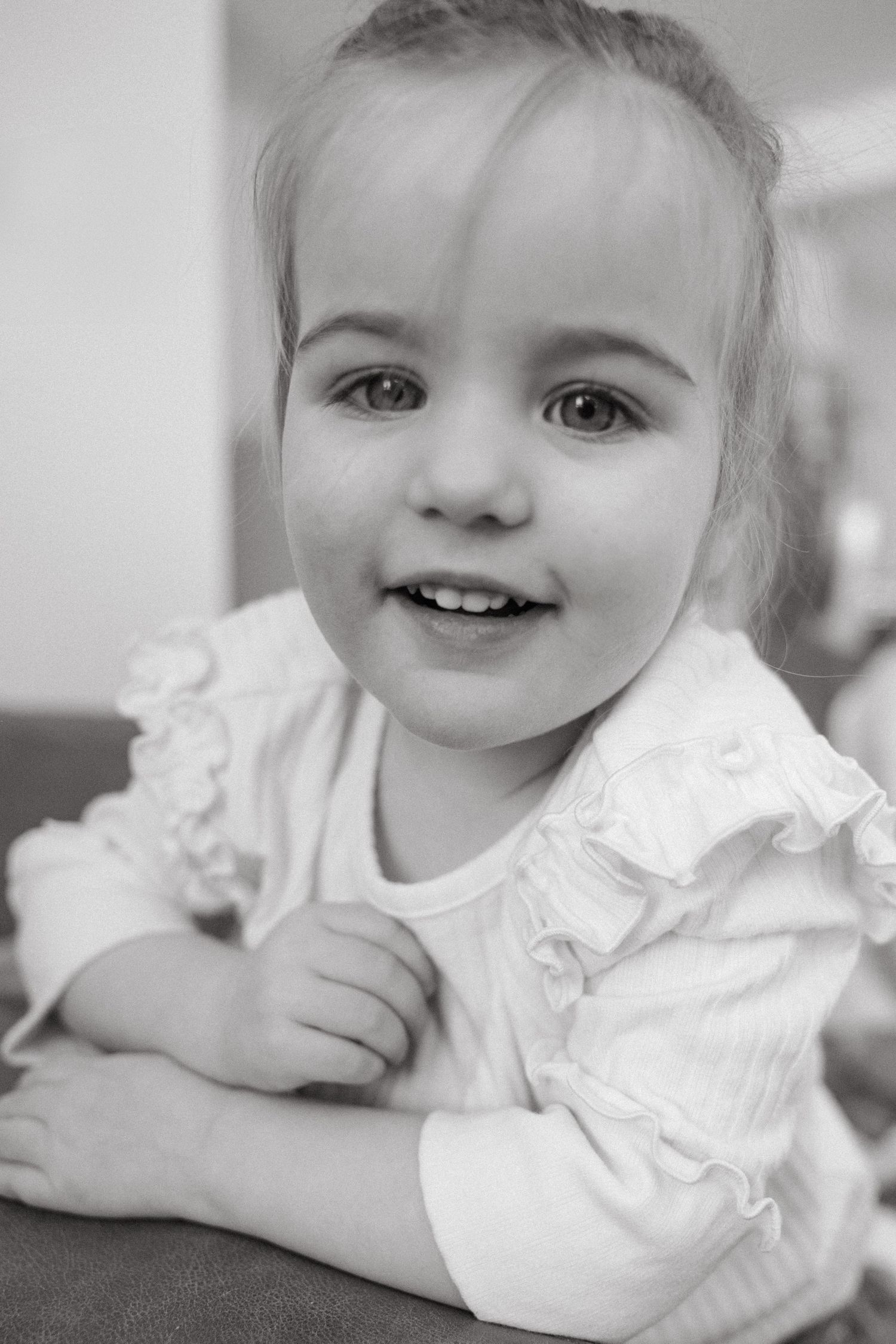 Black and white portrait series showing a baby in white clothing smiling and laying down.