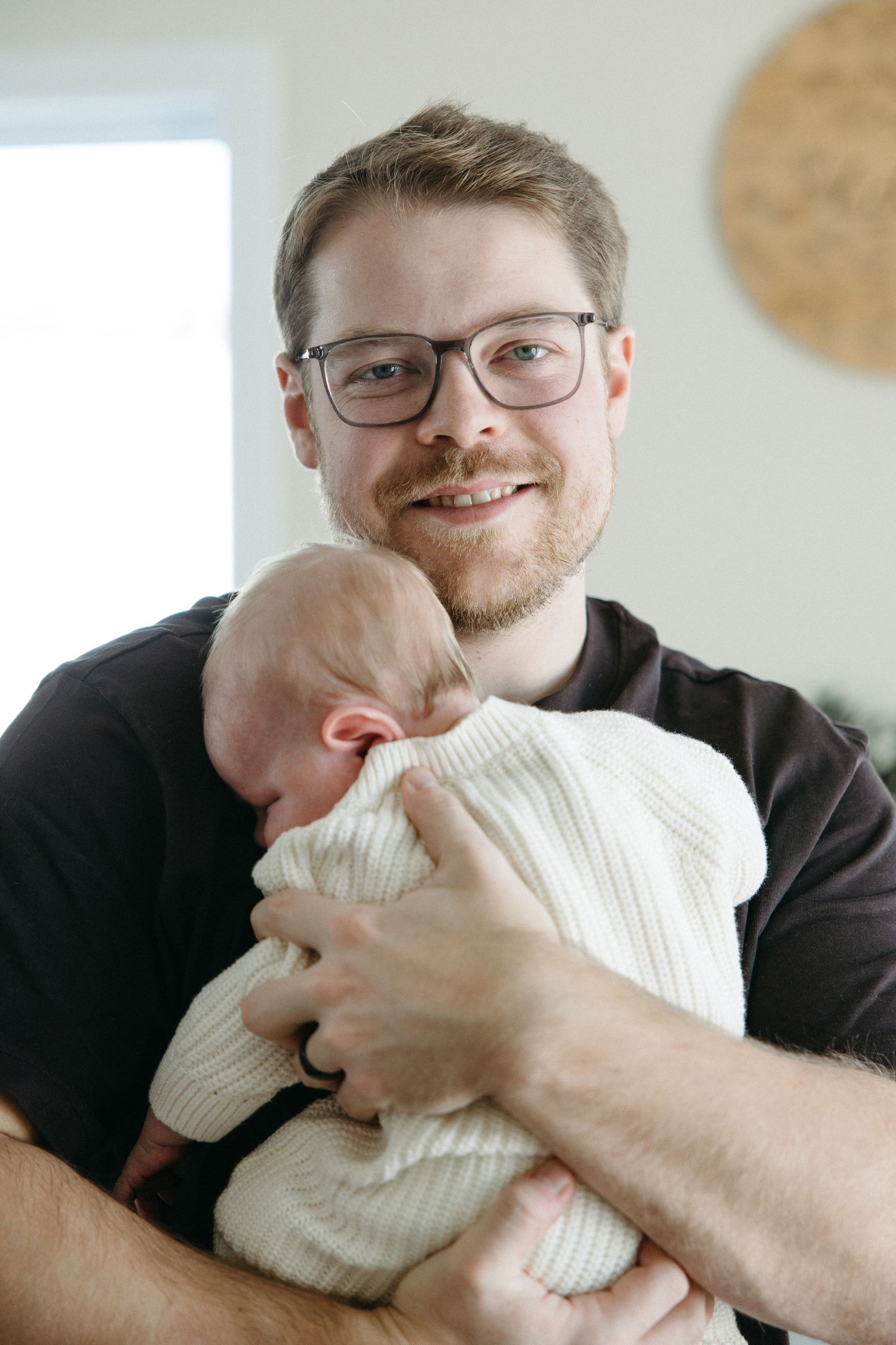 Person in black shirt hugging and nuzzling a white knit pillow while smiling.