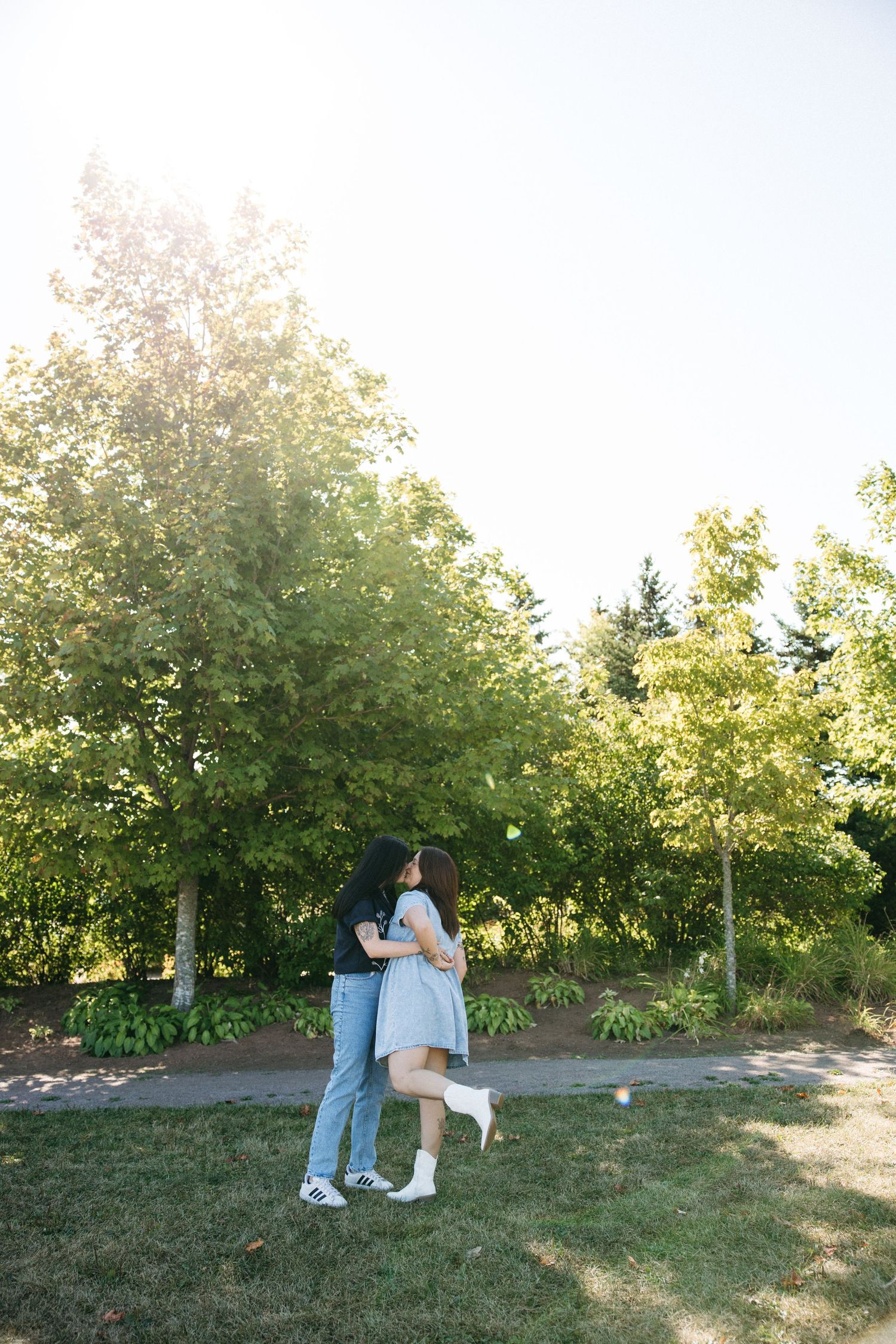 A romantic embrace in a sunny park with green trees and natural lighting.