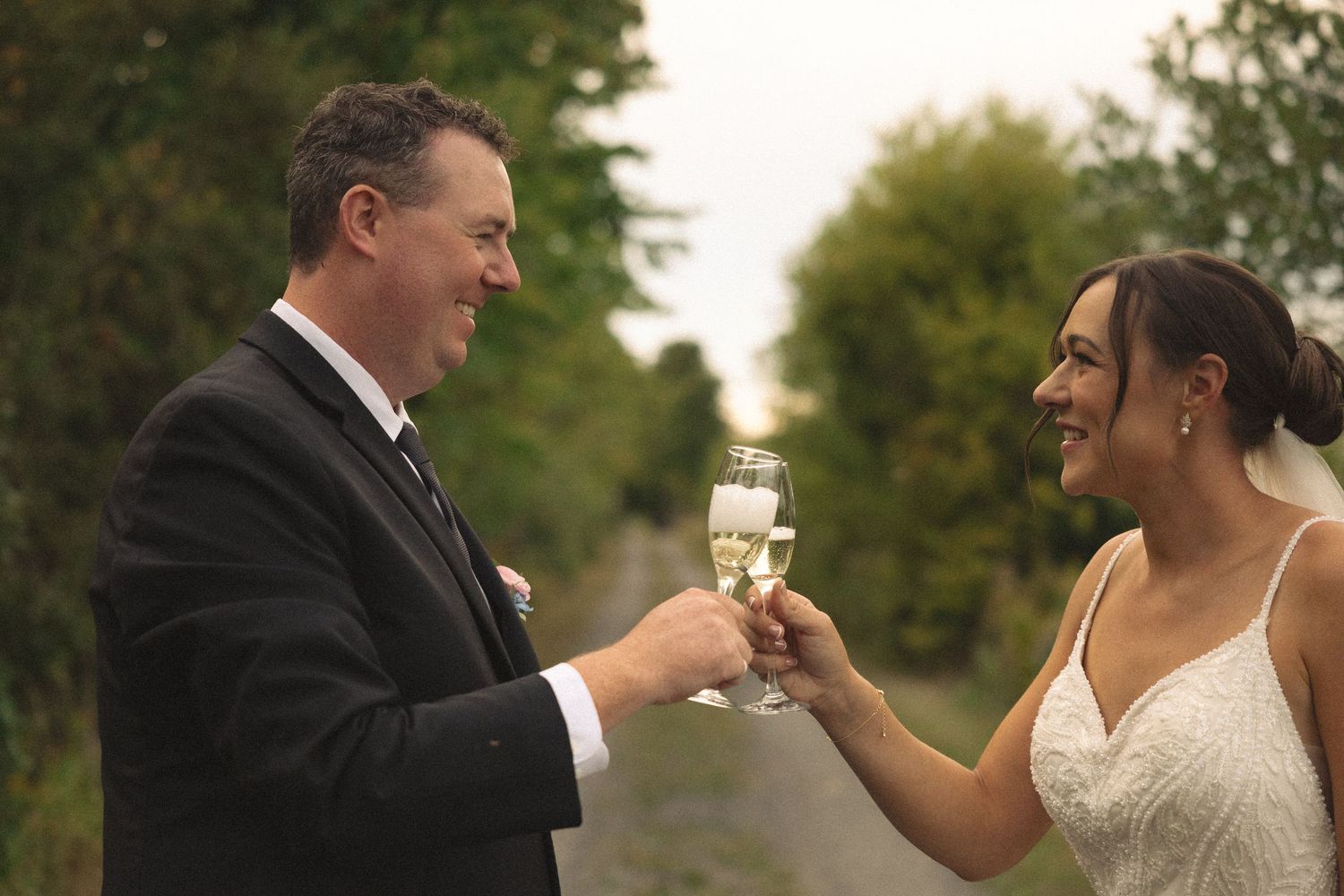 Couple toasting champagne glasses together during their outdoor wedding celebration.