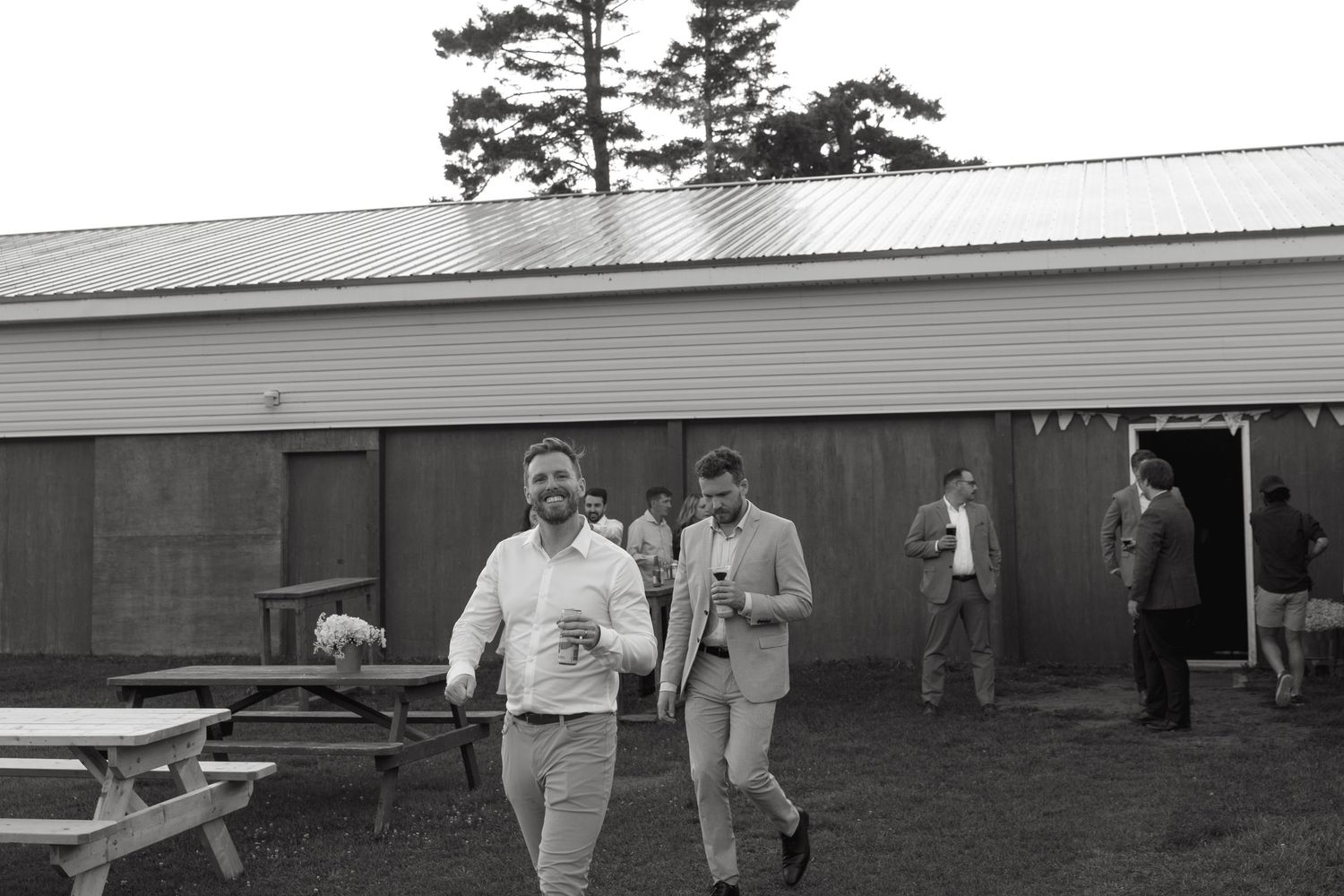 A panoramic view of a rustic barn venue with guests gathering outside.