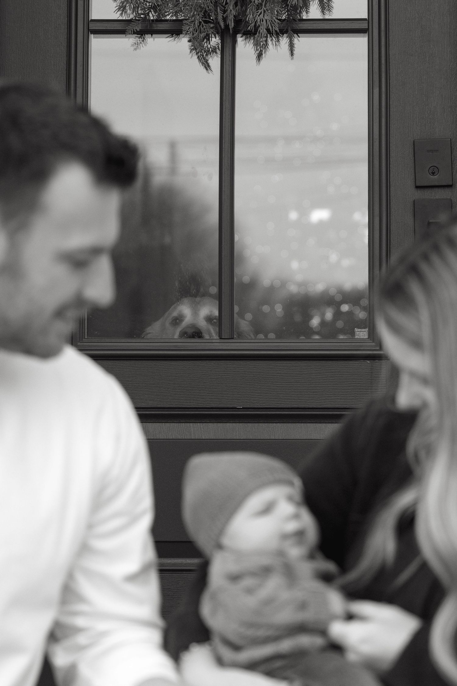 Black and white photo of people relaxing by a window with city lights visible outside.