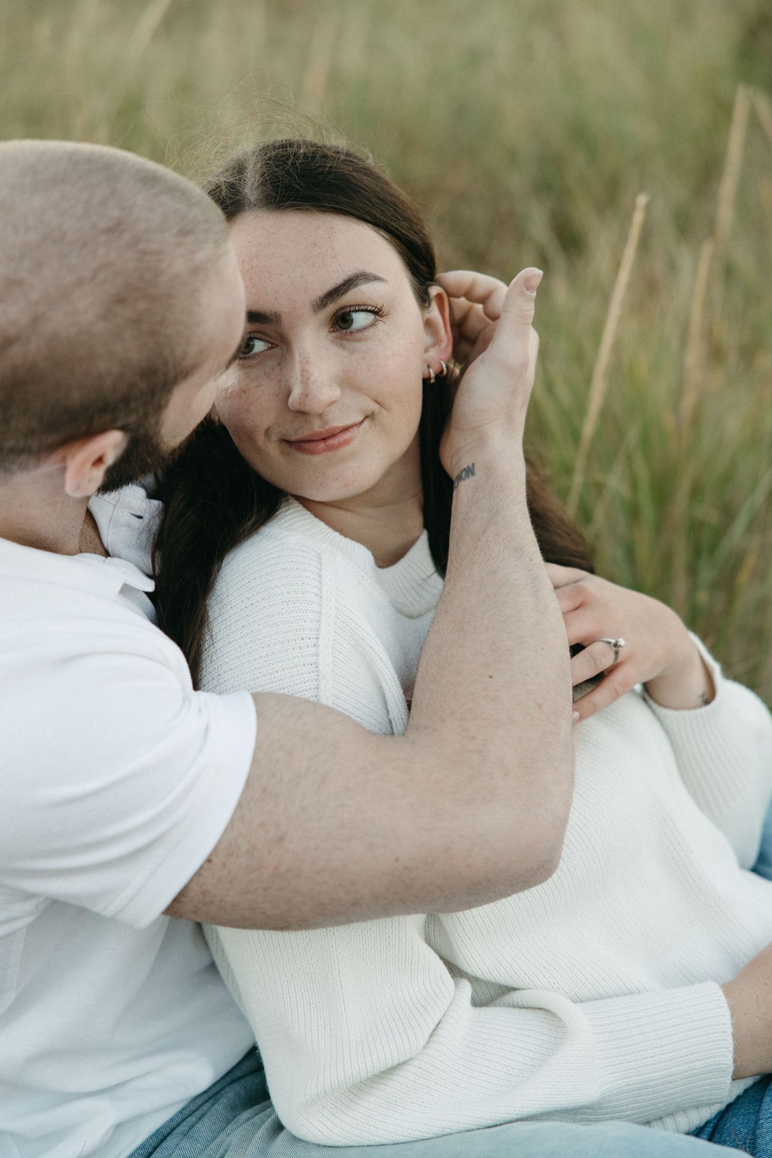 Intimate portrait session in coastal grass during golden hour.