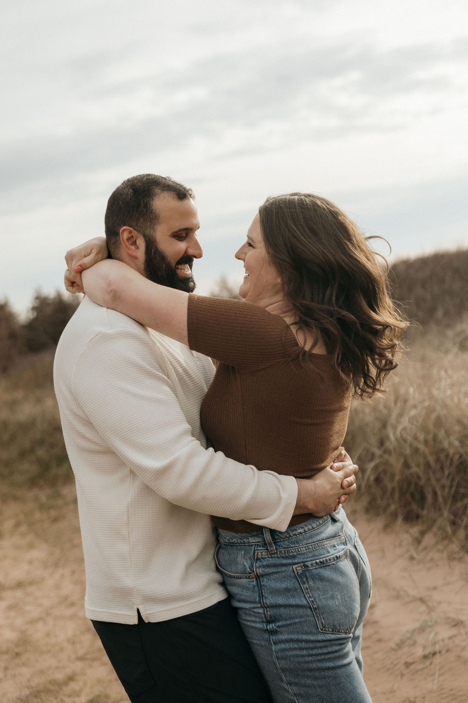 A couple embraces lovingly in a field during an overcast day, their silhouettes captured in a series of intimate moments.