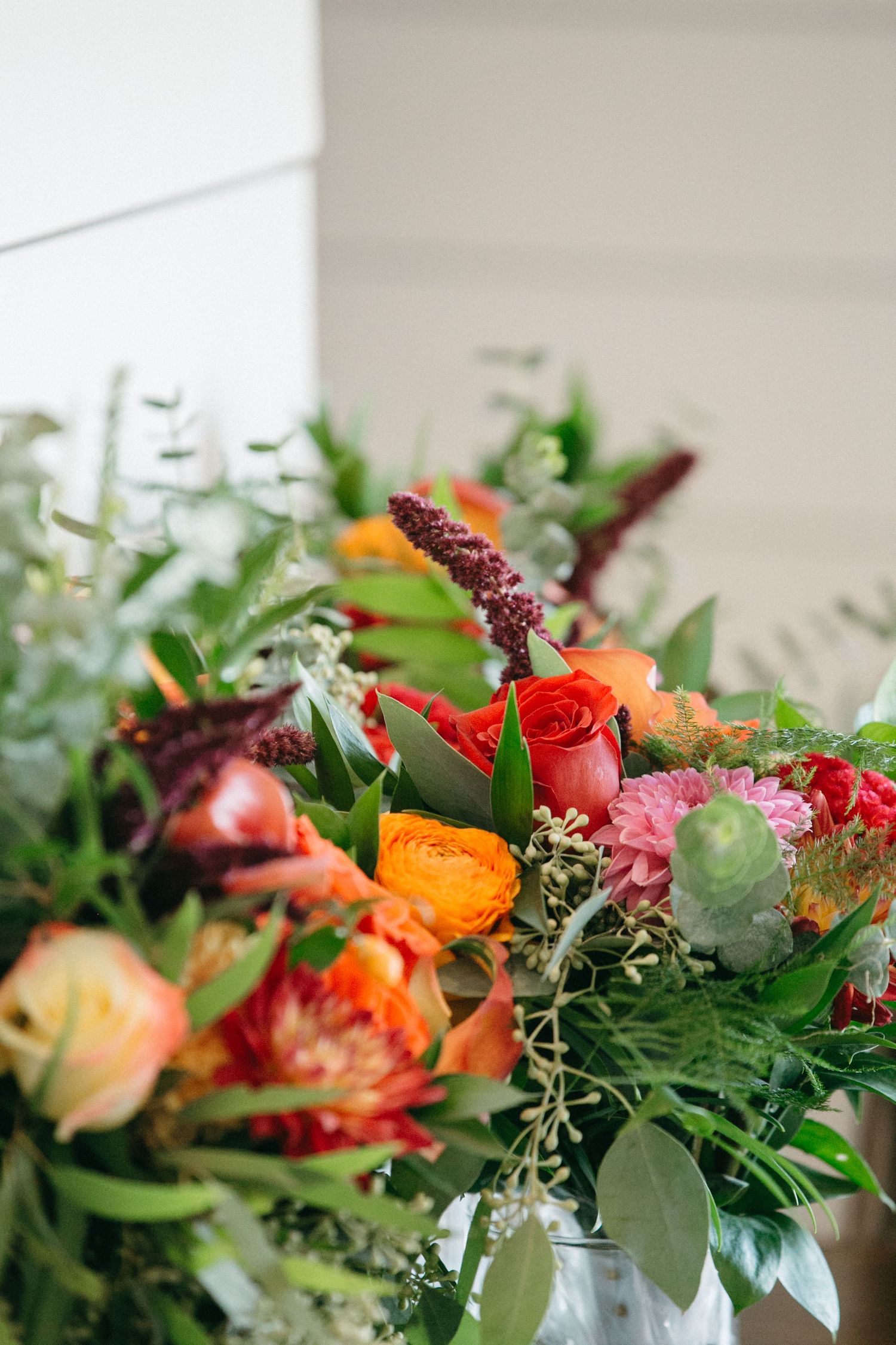 Vibrant floral arrangement with red and orange roses mixed with greenery in a close-up view.