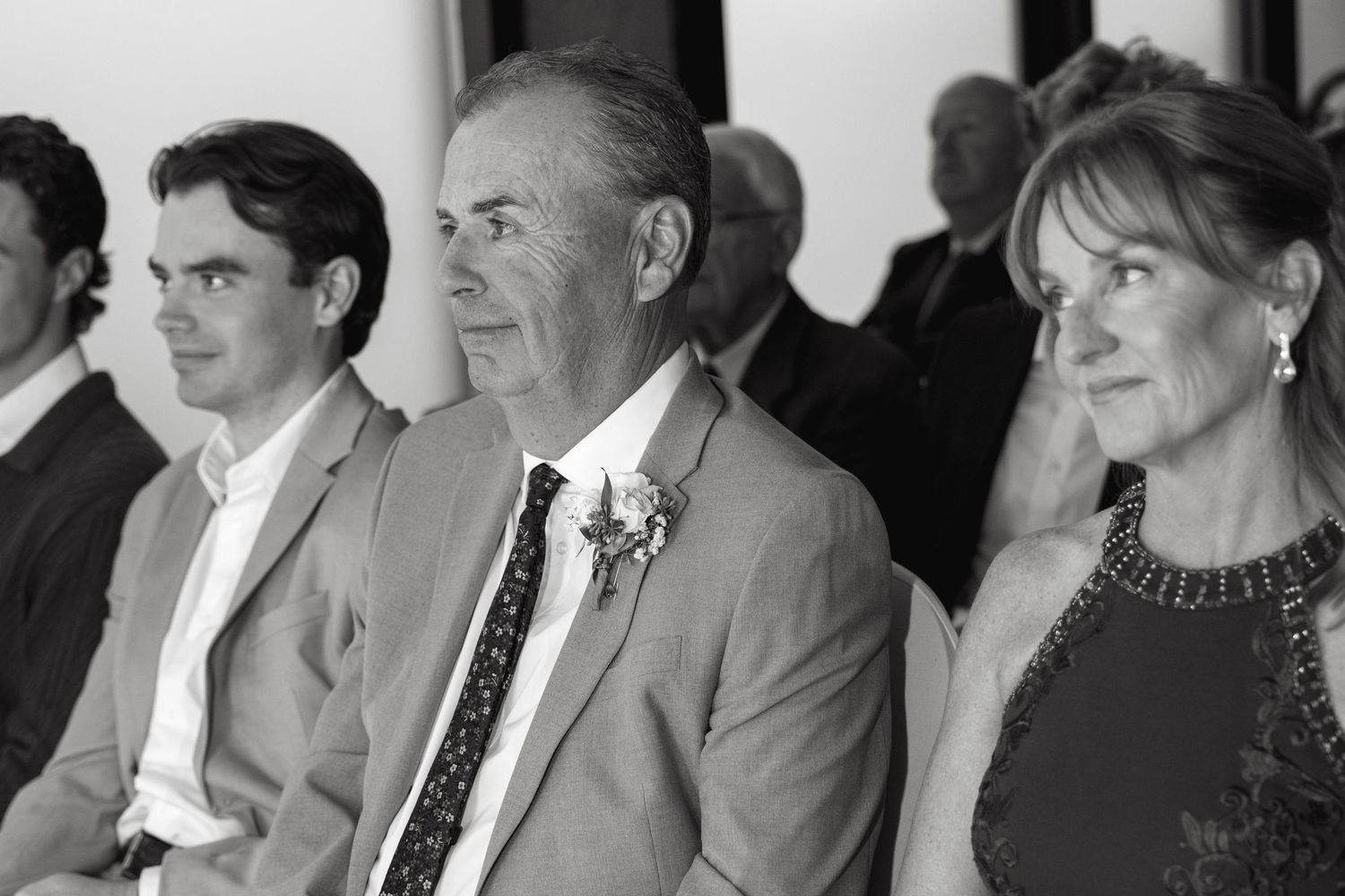 Wedding ceremony guests seated in formal attire watching the proceedings.