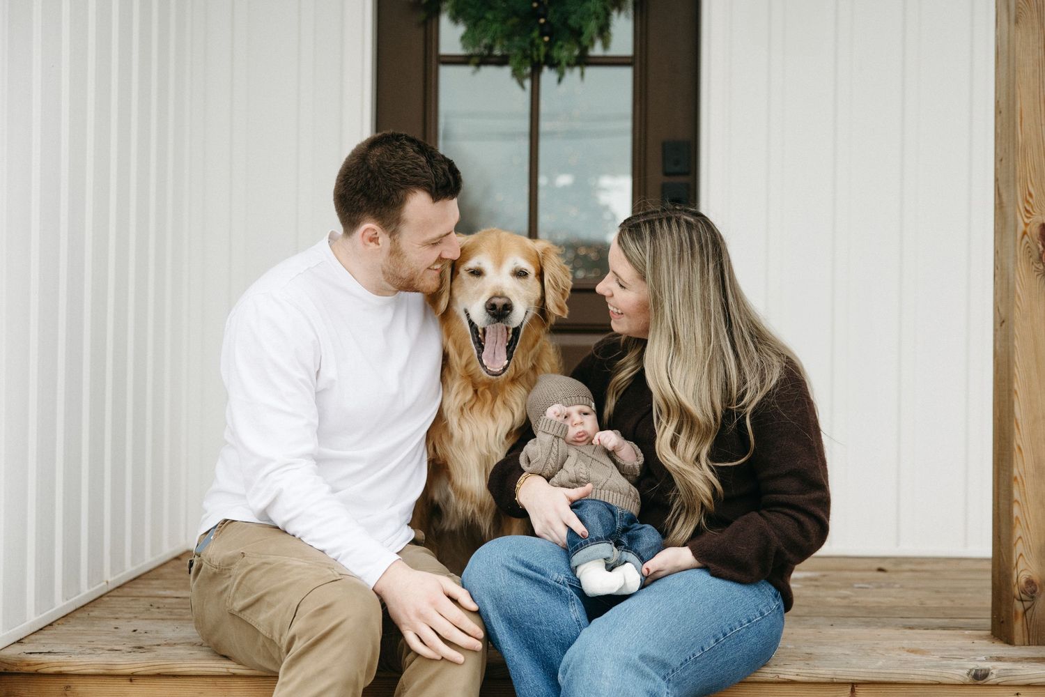 A family relaxes together on a rustic porch with their golden retriever nearby.