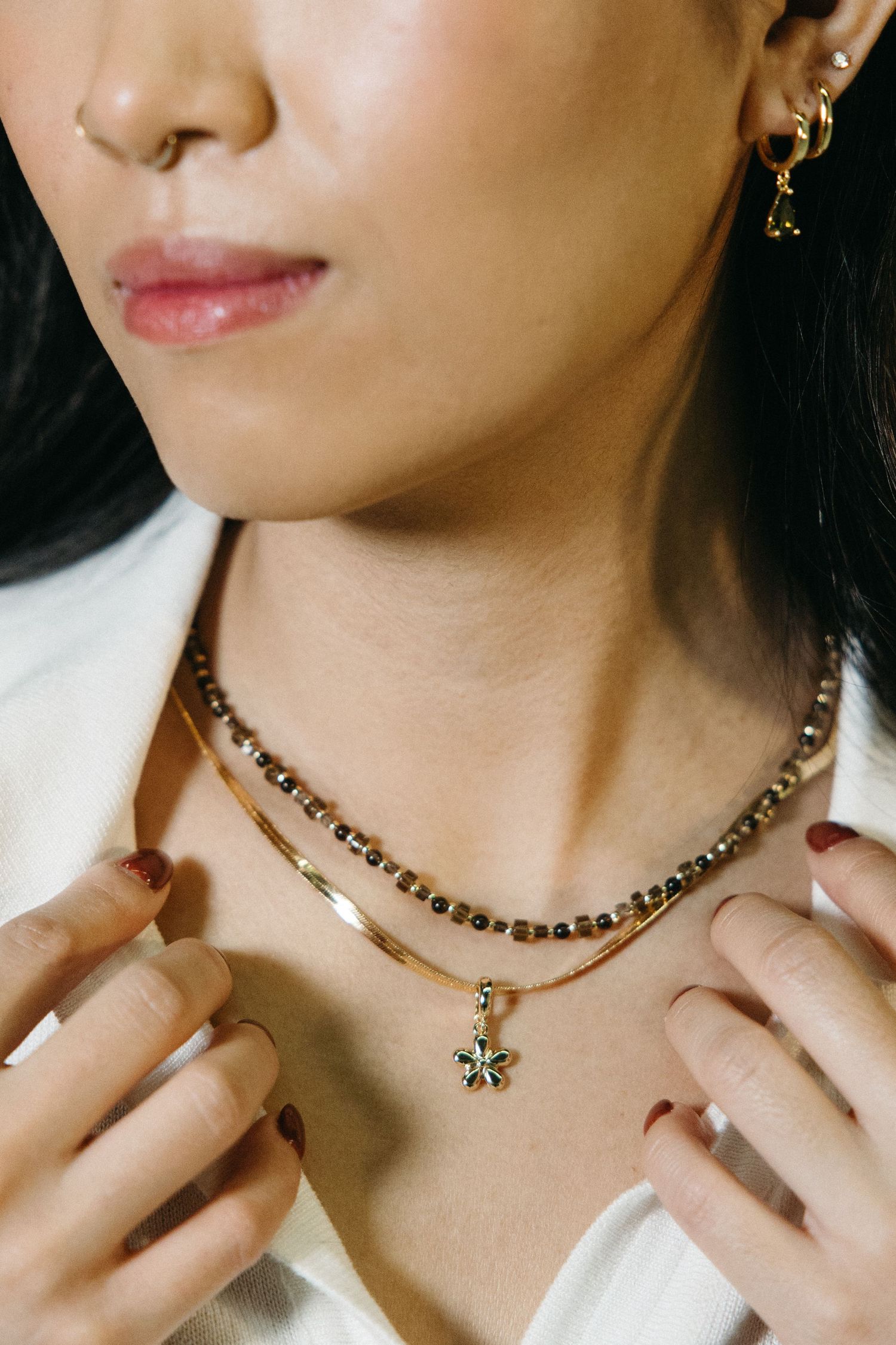 Close-up of beaded choker necklace with pendant detail in warm lighting.