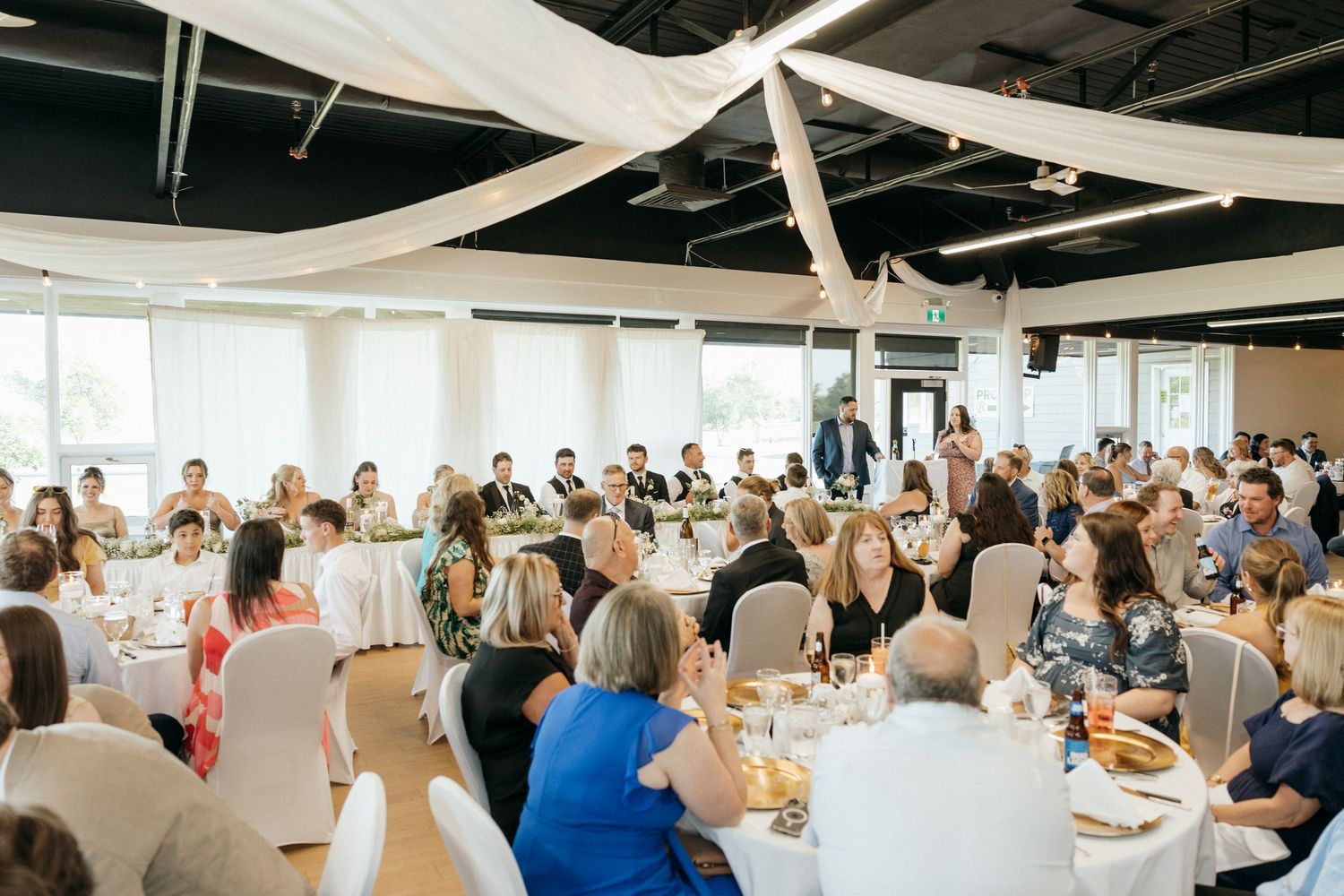 Large conference room filled with attendees seated at round tables during an event.