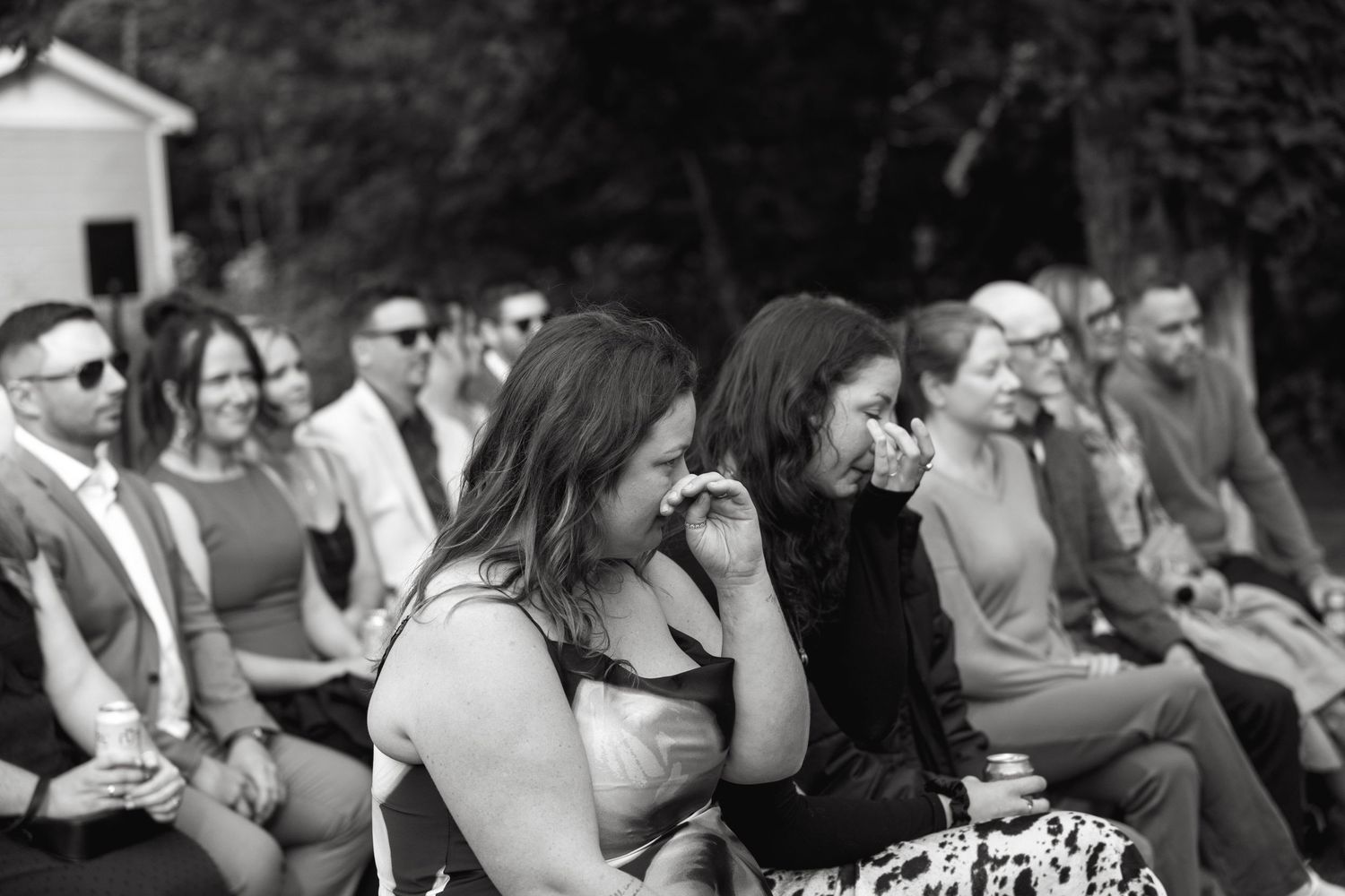 Black and white photo of wedding guests watching ceremony from wooden benches.