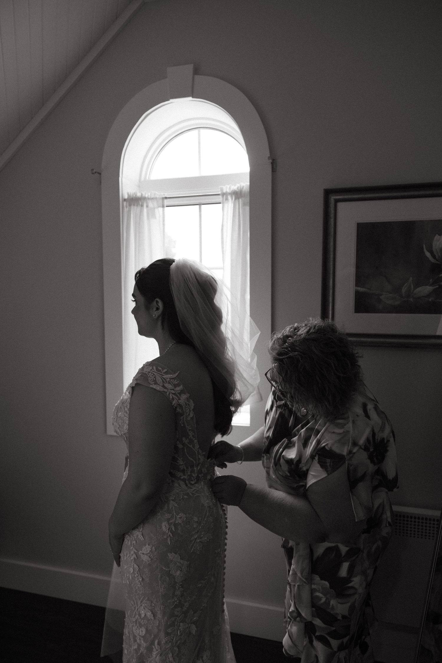Silhouetted figures by arched window during wedding preparations.