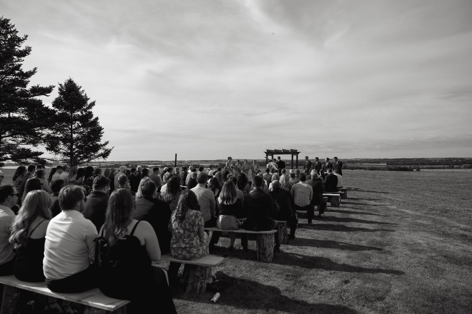 Panoramic view of outdoor wedding ceremony setup with benches overlooking the ocean.