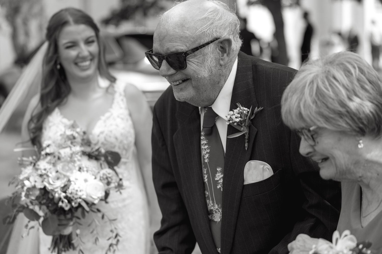 Wedding party members share joyful moments during outdoor celebration.