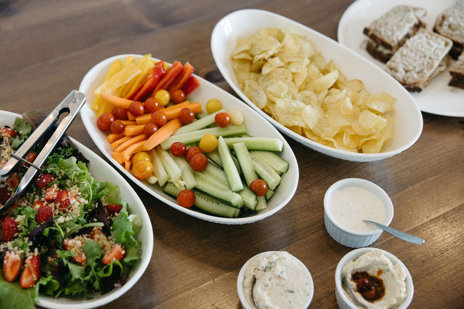 Assorted fresh vegetables, salads and side dishes arranged on a wooden table.