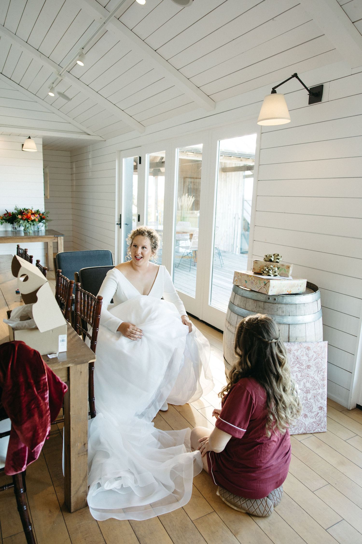 Wedding dress preparation in a white-paneled room with rustic decor.