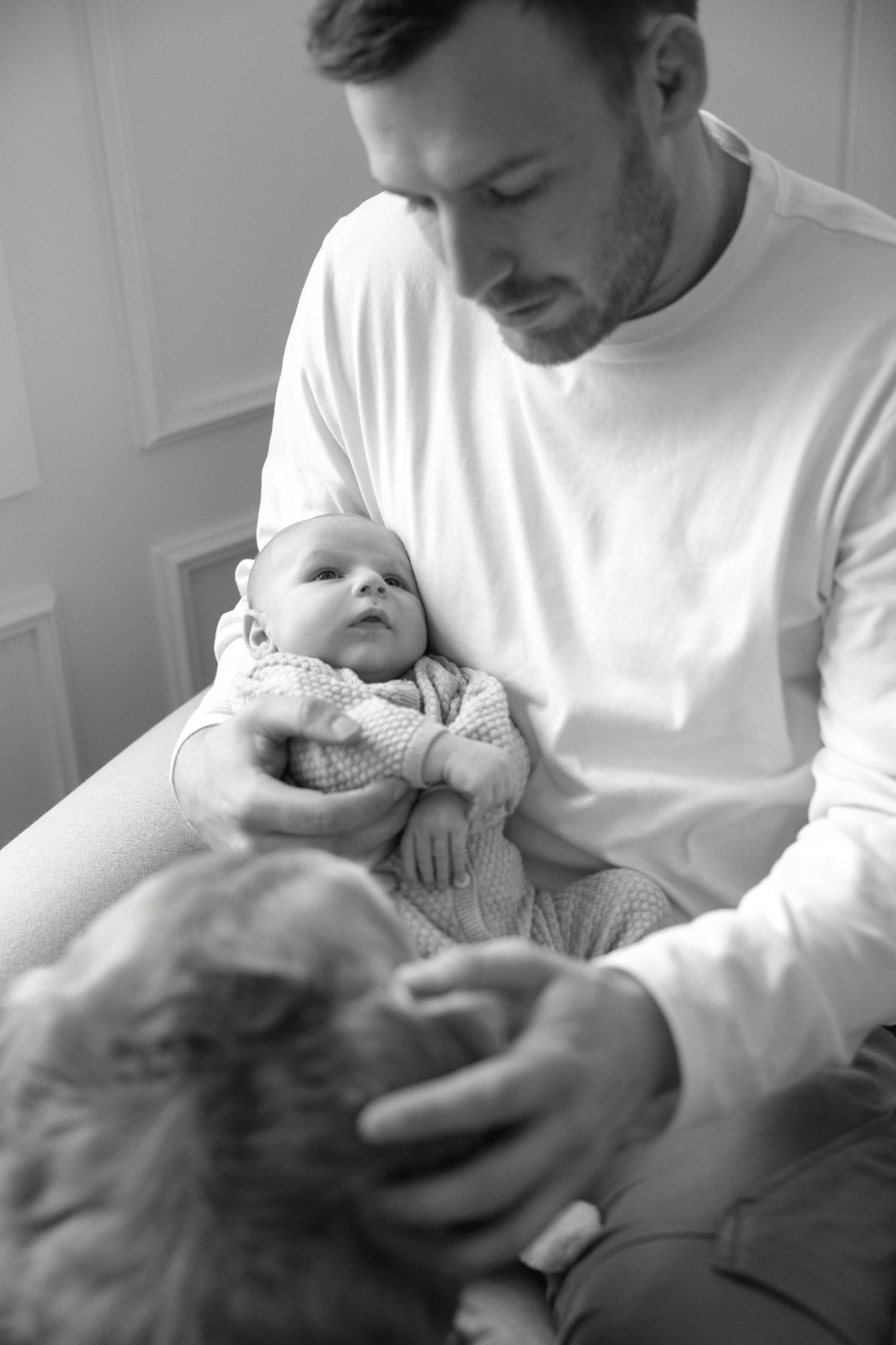 Tender black and white moments between baby and caregiver on couch.