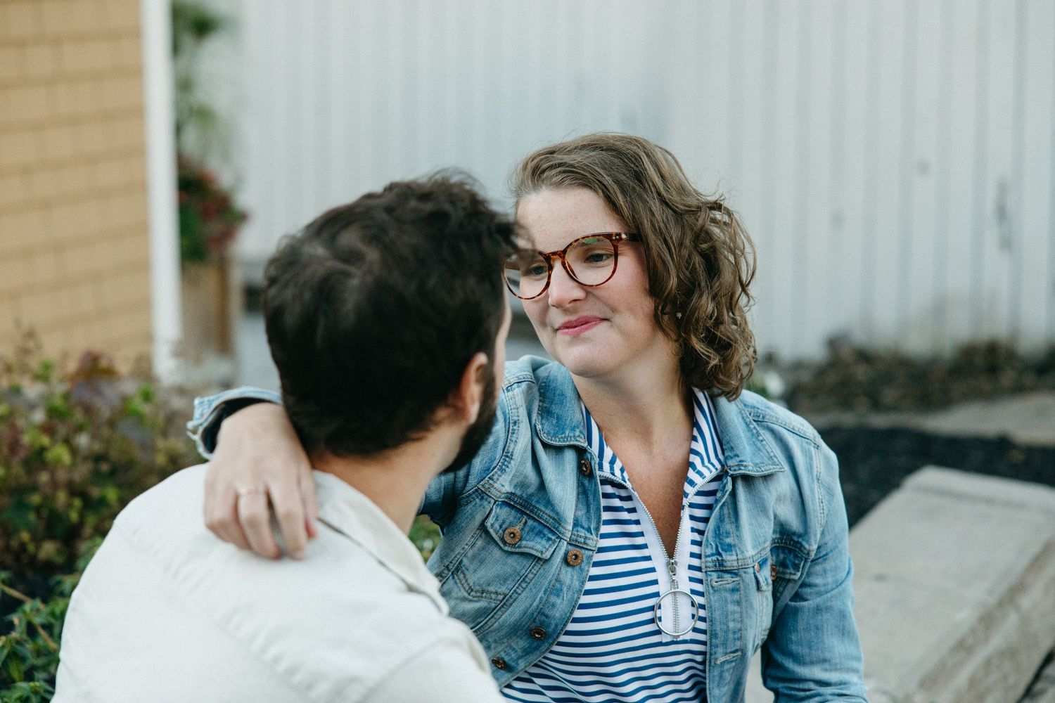 Two people share an intimate moment while sitting together outdoors.