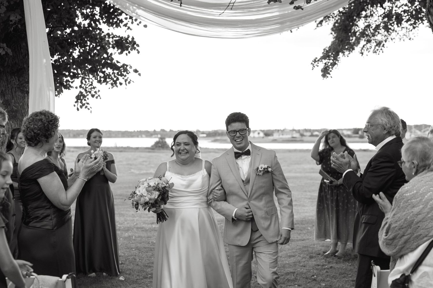 Bride and groom walk back down the aisle after their outdoor wedding ceremony in black and white photo.
