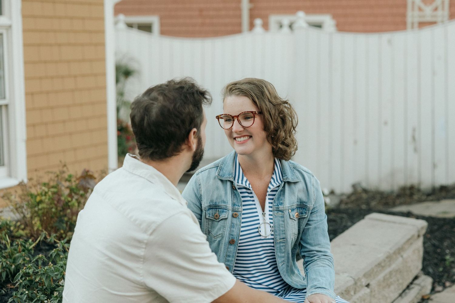 Two people share a romantic moment while sitting on steps outside a house.