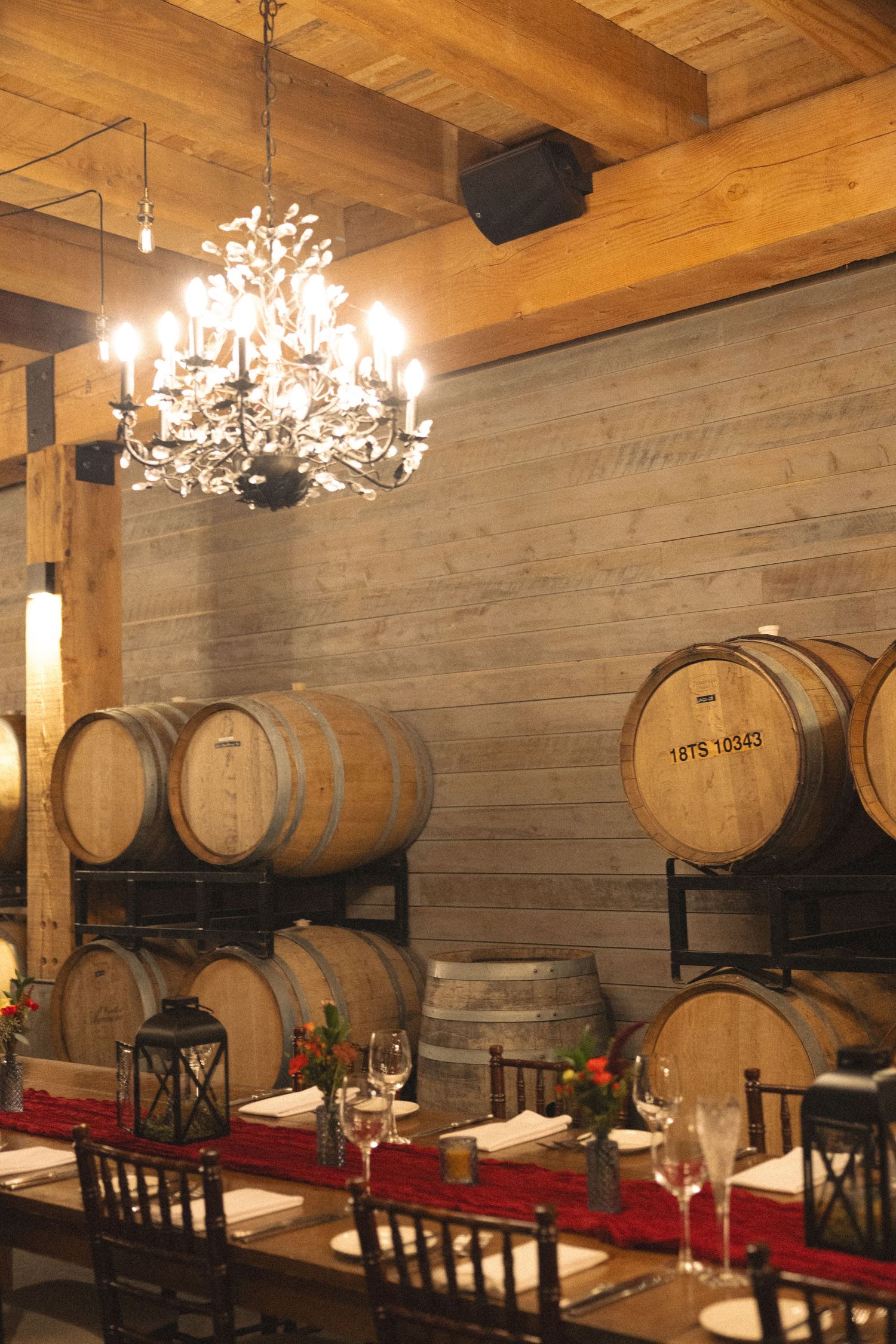 Elegant winery dining room with wooden barrels, chandelier, and table set with red runner.