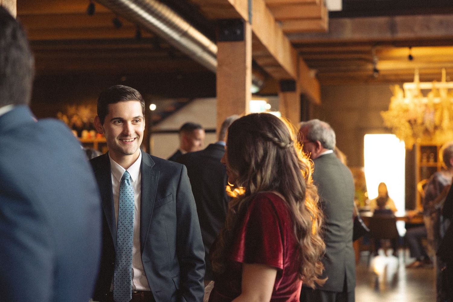 People gathered at an indoor event with warm lighting and exposed wooden beams.