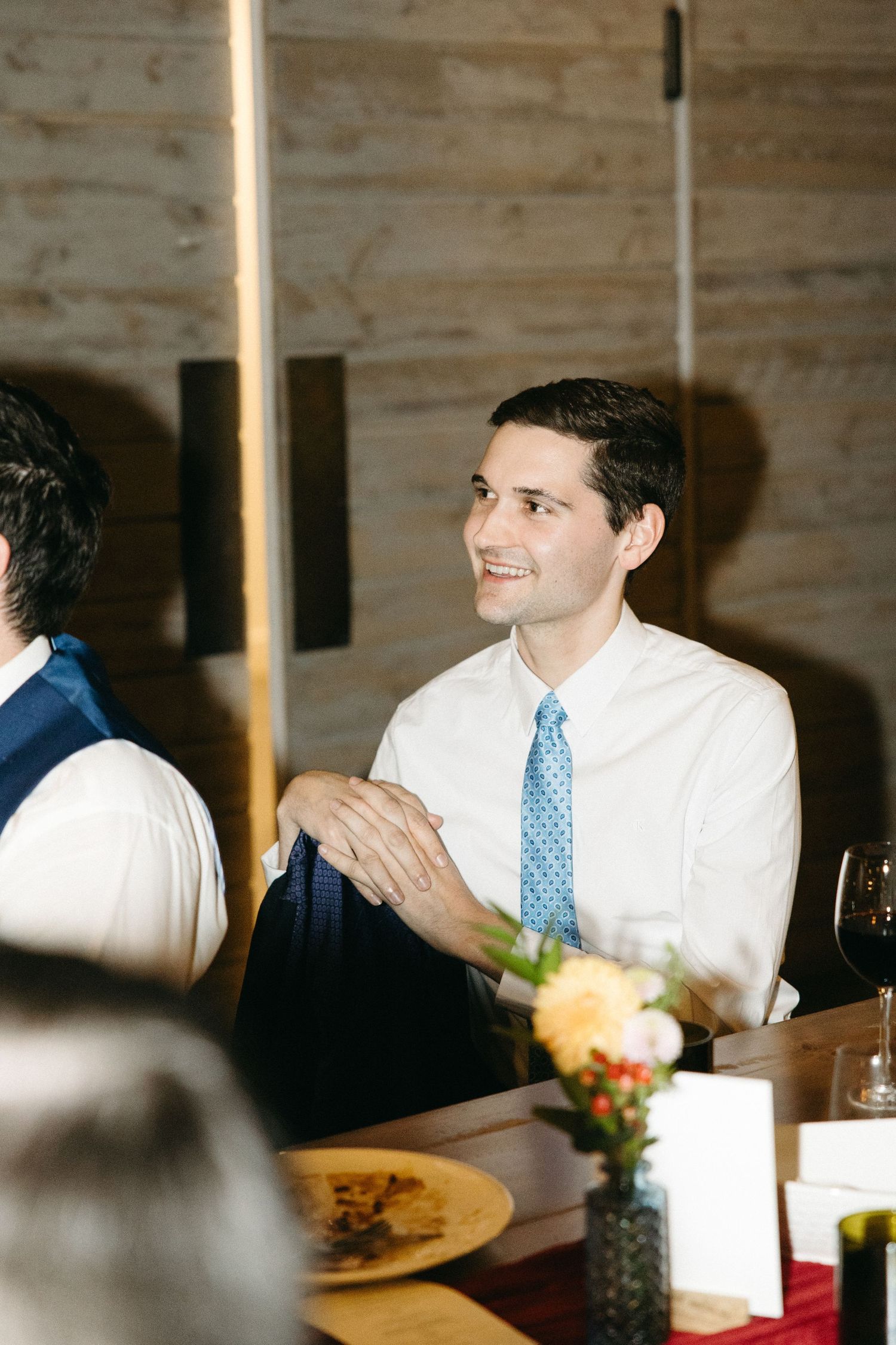 Dinner guest in white shirt and blue tie smiling during wine cellar event.