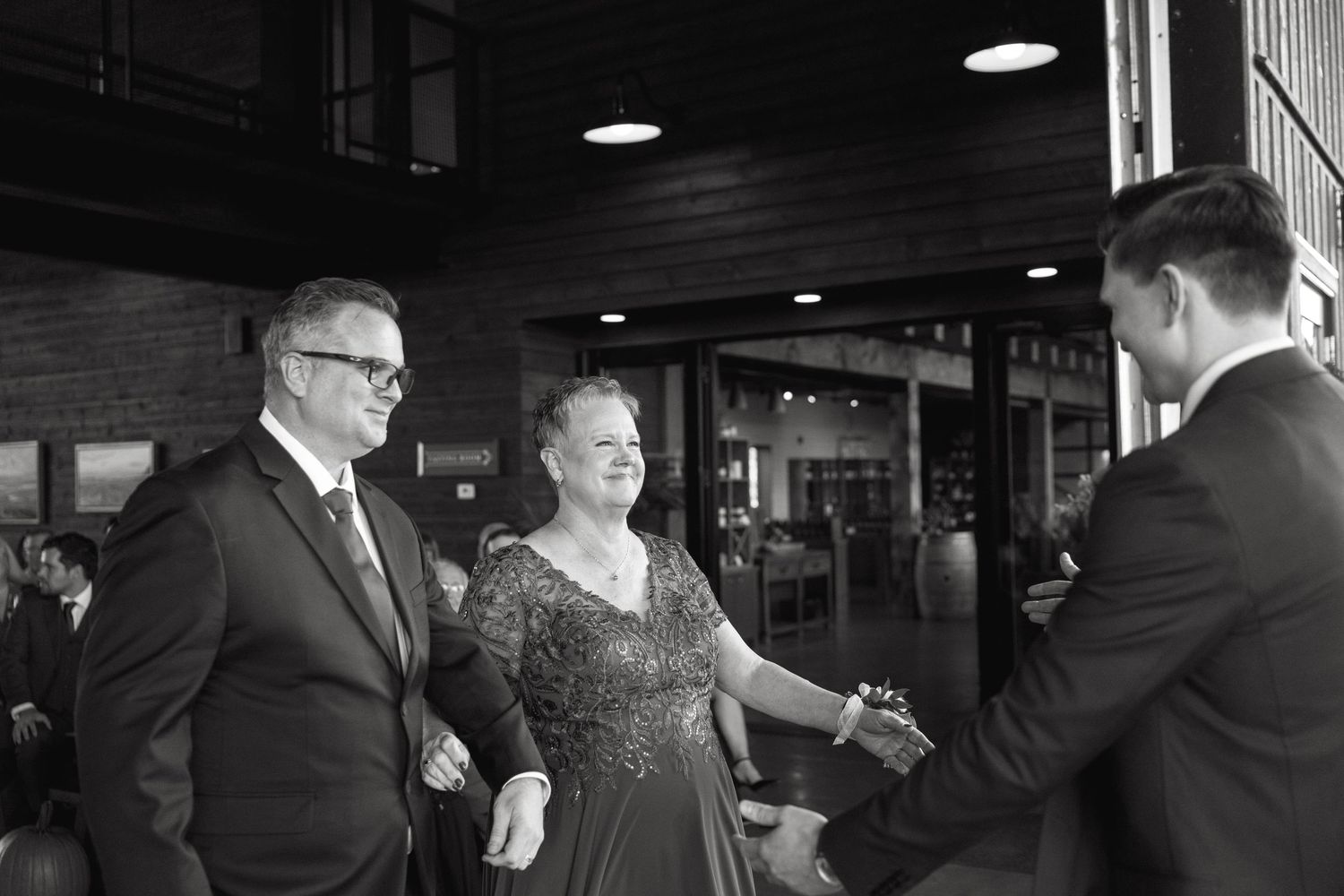 Wedding guests mingle in a dimly lit indoor reception space.