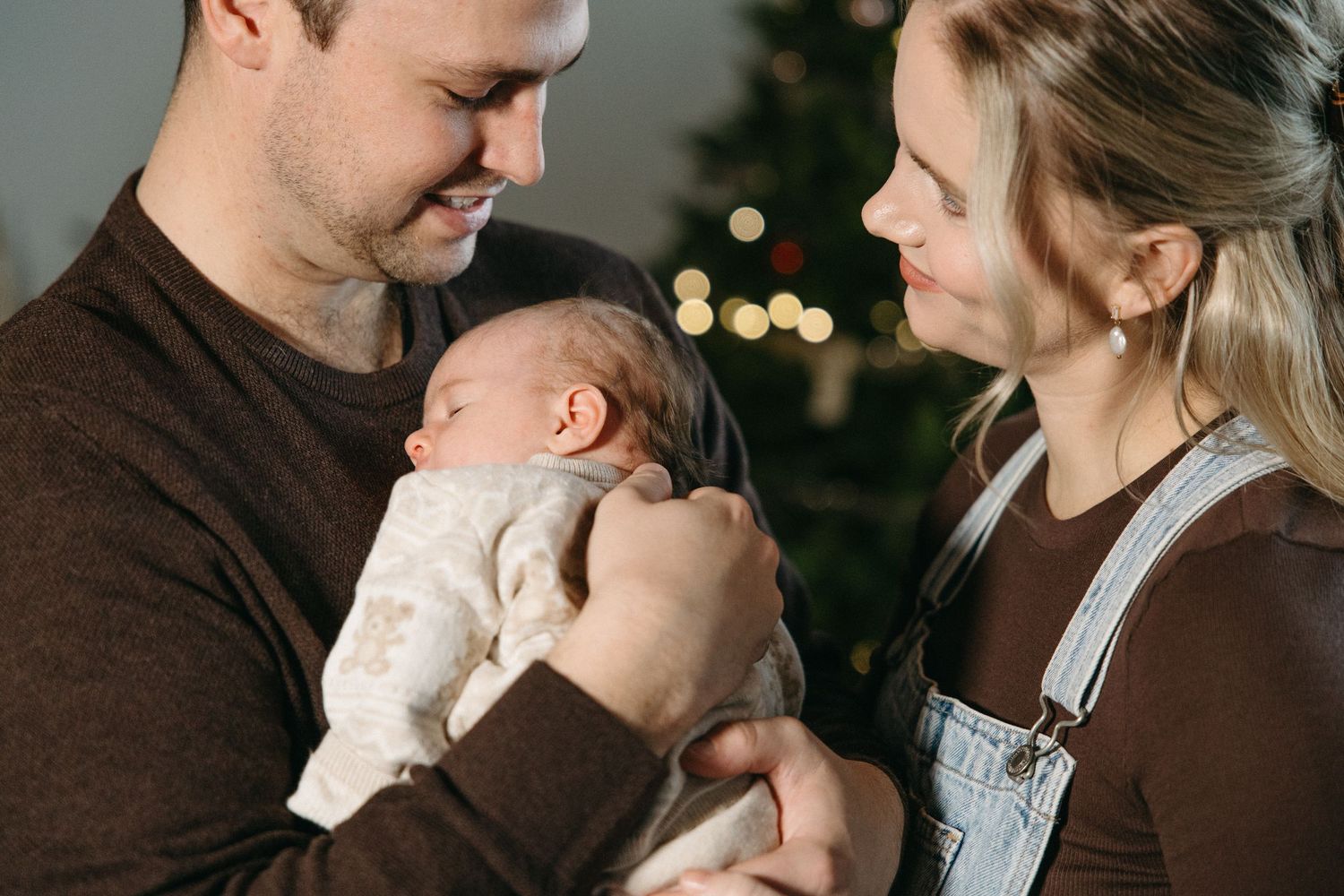 Family enjoying intimate moments together in front of Christmas lights during a winter photoshoot.