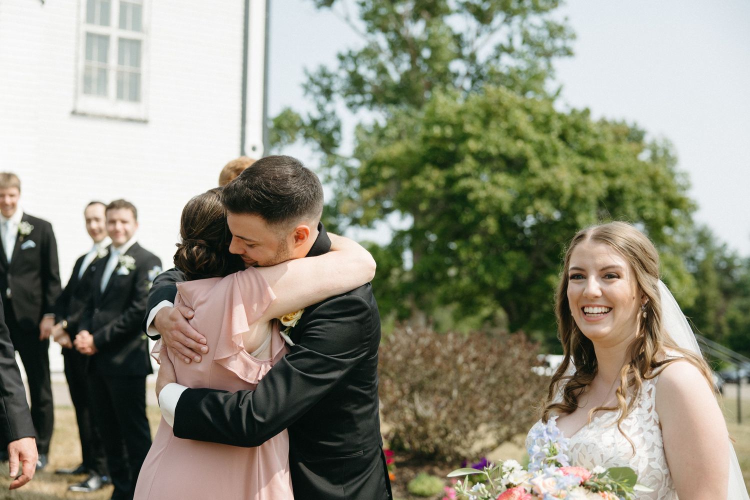 Outdoor wedding celebration with guests mingling on sunny day.