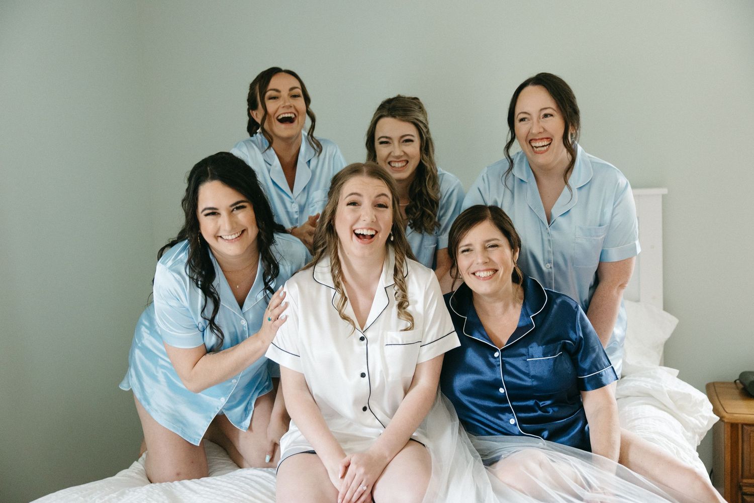 Friends in coordinated pajamas enjoying a lighthearted moment together on a bed.