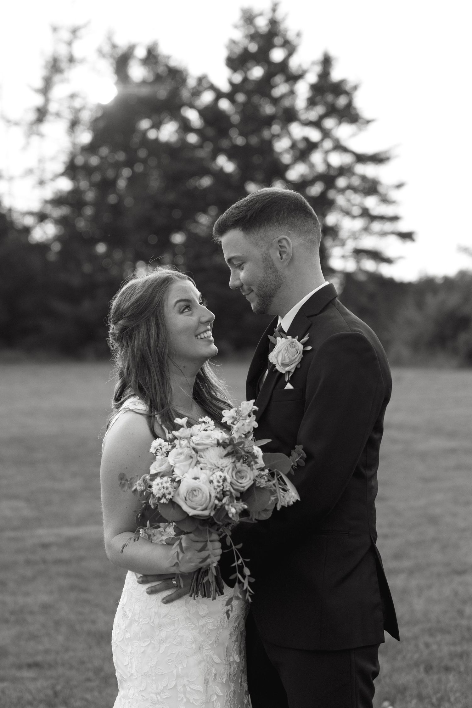 Romantic wedding couple poses together in an outdoor field during golden hour.