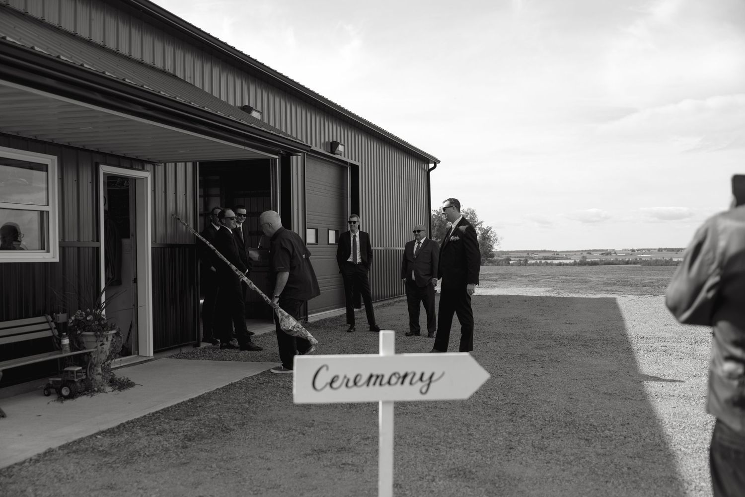 People gathering outside a building with a ceremony direction sign.