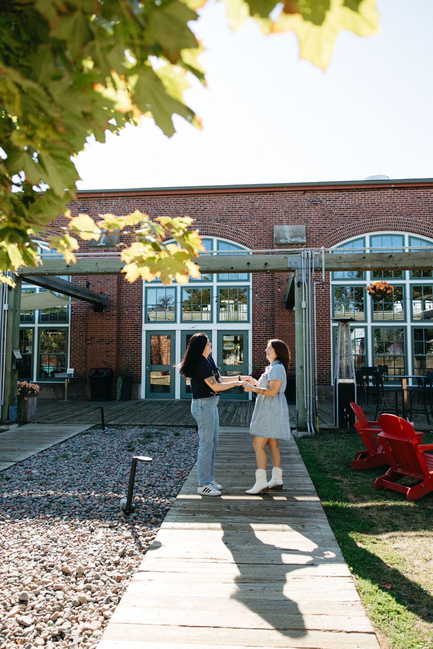 People interacting outside a brick building with red chairs visible in the background.