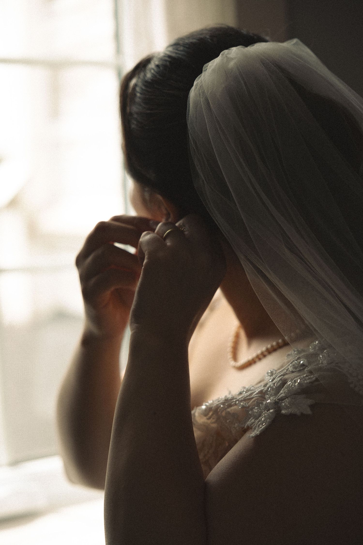A silhouetted side profile of wedding preparations in a sunlit room.