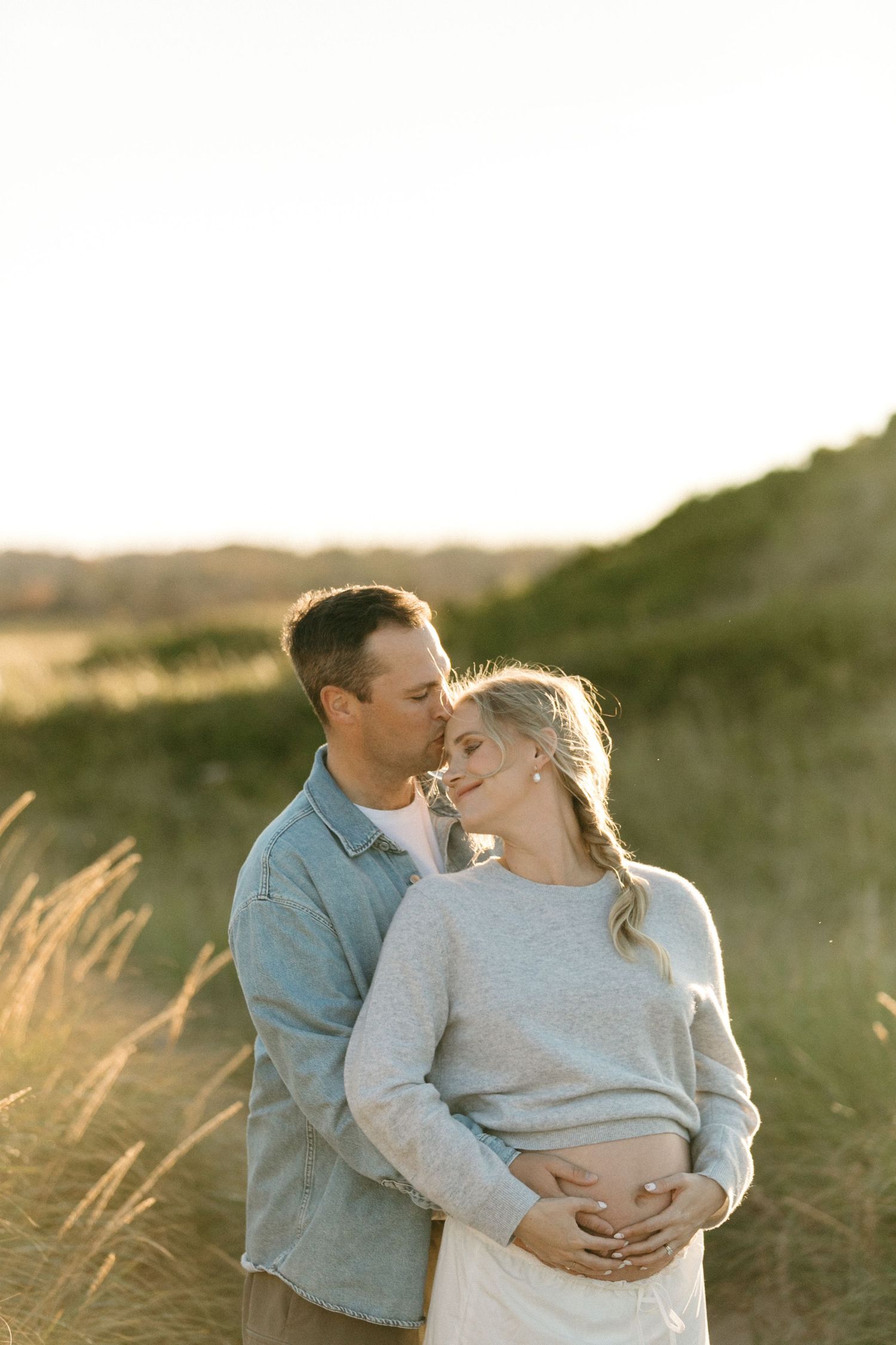 A tender embrace captured during a maternity photoshoot in golden hour lighting.