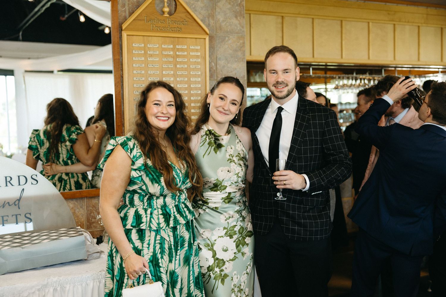 Wedding party members in green floral dresses celebrating indoors.