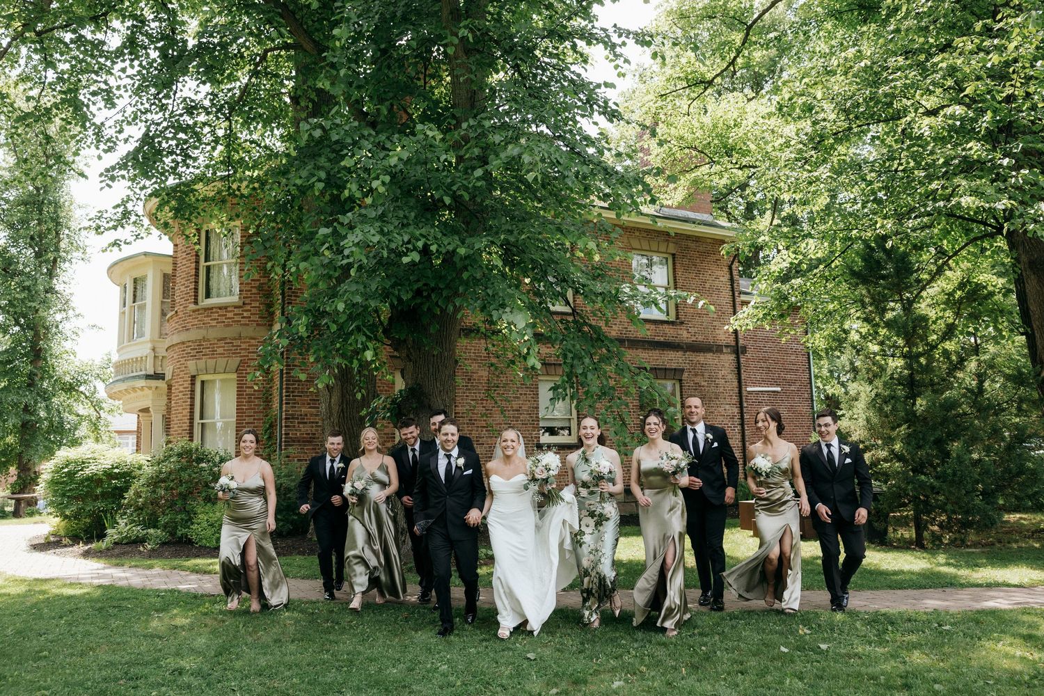 Wide angle shot of wedding party and guests gathered on landscaped grounds.